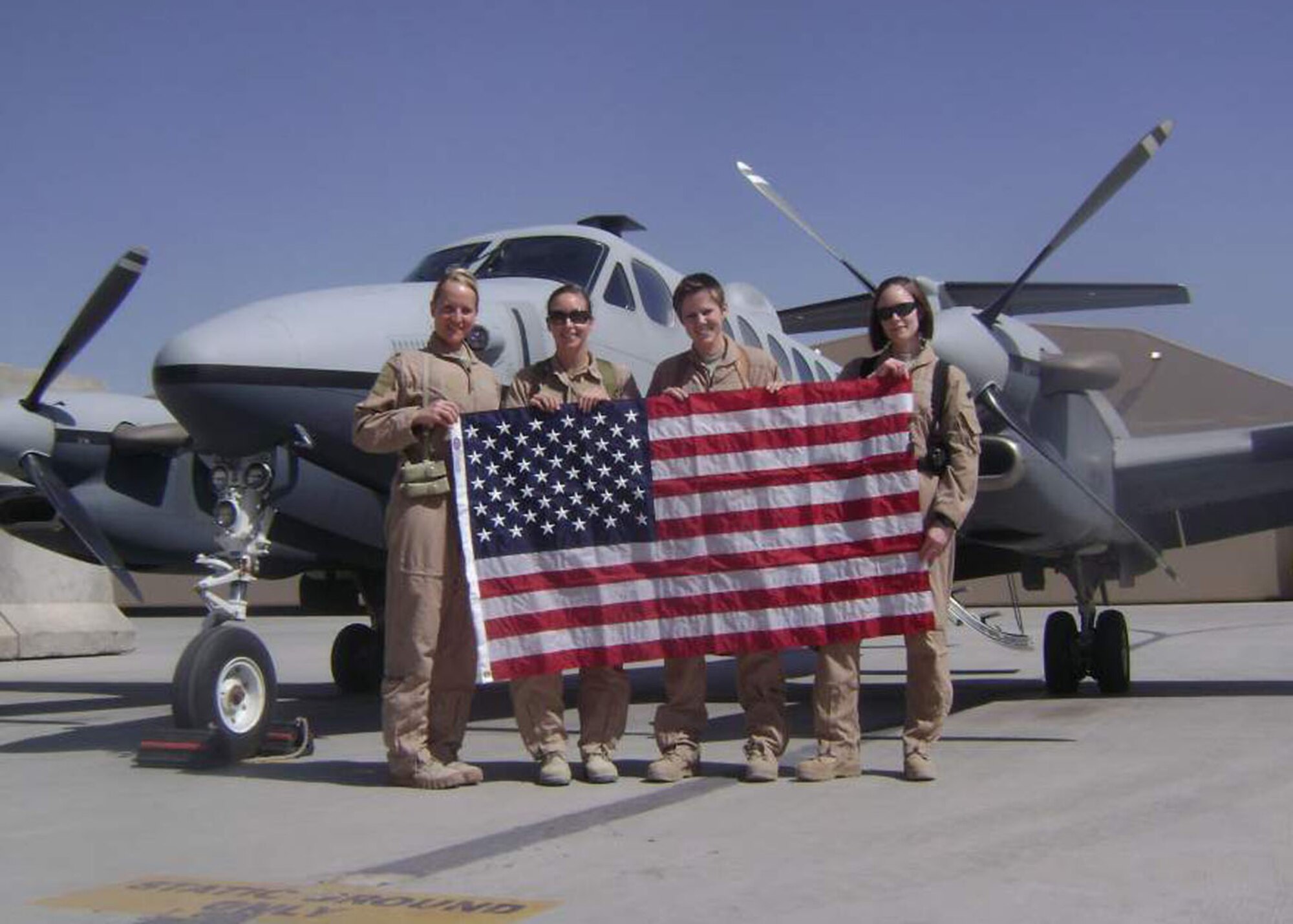 From left, Maj. Sharon Rohde, Royal Australian air force Flt. Lt. Carlene
Heise, Senior Airman Heather Eichbrecht, and Staff Sgt. Stephanie Wiggins
from the 361st Air Expeditionary Squadron hold up a U.S. flag after flying
an Operation Enduring Freedom combat mission on an MC-12W in commemoration
of International Women's Day at Kandahar Airfield, Afghanistan, March 8,
2012.  The MC-12W is a $22.5M highly modified tactical Intelligence,
Surveillance and Reconnaissance aircraft that plays a critical role in
removing high-value individuals from the battlefield.
(Photo courtesy of Lt. Col. James Sweeney, 361st Air Expeditionary Squadron commander)
