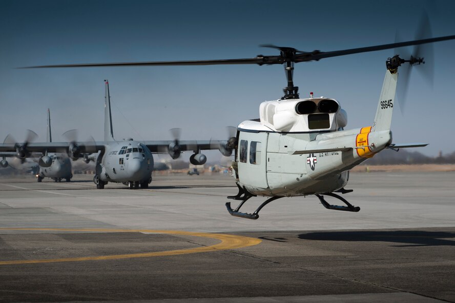 YOKOTA AIR BASE, Japan -- A UH-1N Iroquois helicopter lands at Yokota Air Base, Japan, as C-130 Hercules prepare for takeoff March 15, 2012. The 374th Airlift Wing uses UH-1Ns, C-130s and C-12s to perform intra-theater airlift missions within the western Pacific region. (U.S. Air Force photo/Staff Sgt. Samuel Morse)