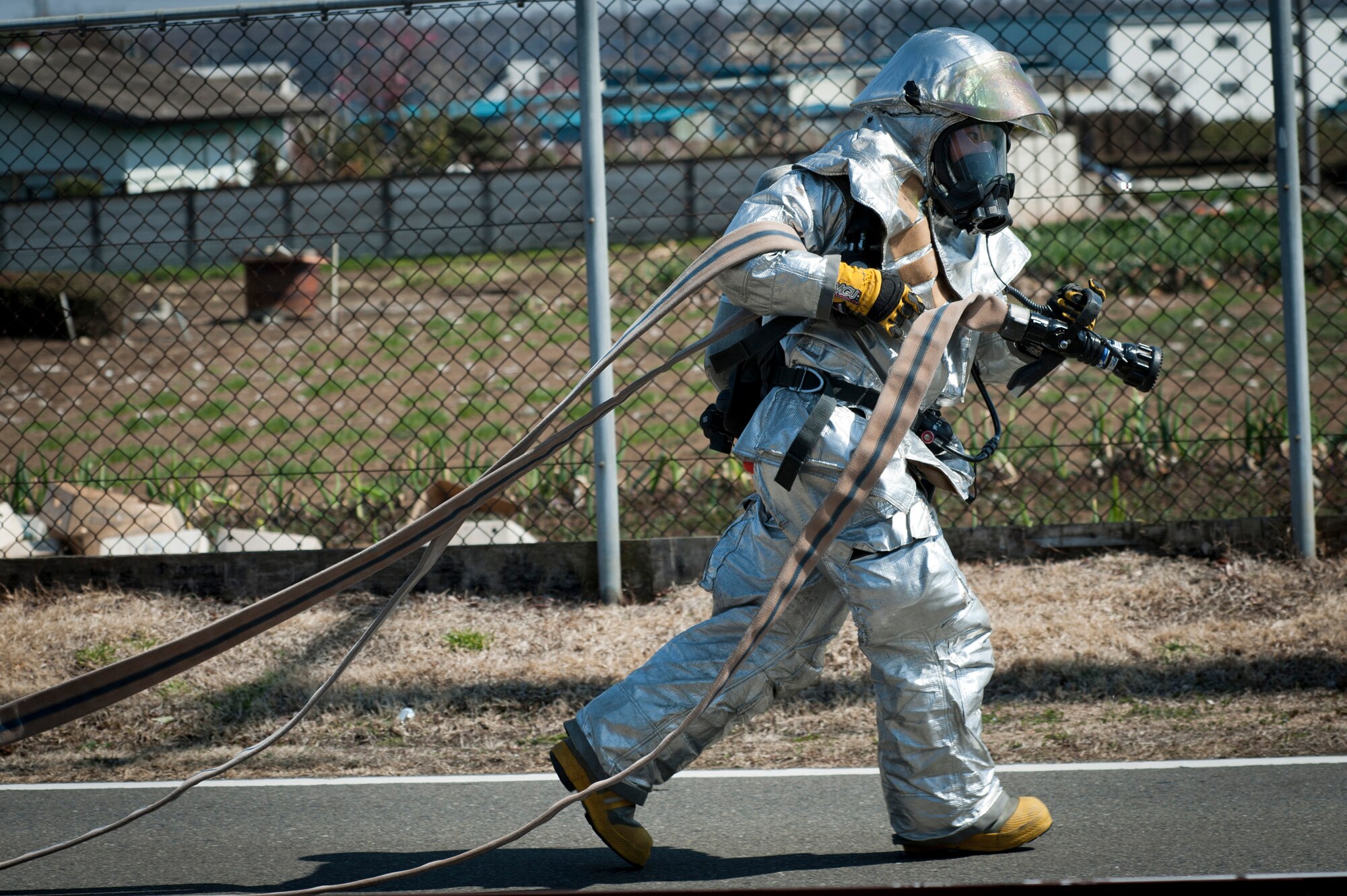 YOKOTA AIR BASE, Japan -- A firefighter from the 374th Civil Engineer Squadron pulls a fire hose toward a simulated fire during an emergency management exercise at Yokota Air Base, Japan, March 14, 2012. The 374th Airlift Wing held the EME to test and train its Airmen to respond to emergencies quickly and effectively. (U.S. Air Force photo/Staff Sgt. Samuel Morse)