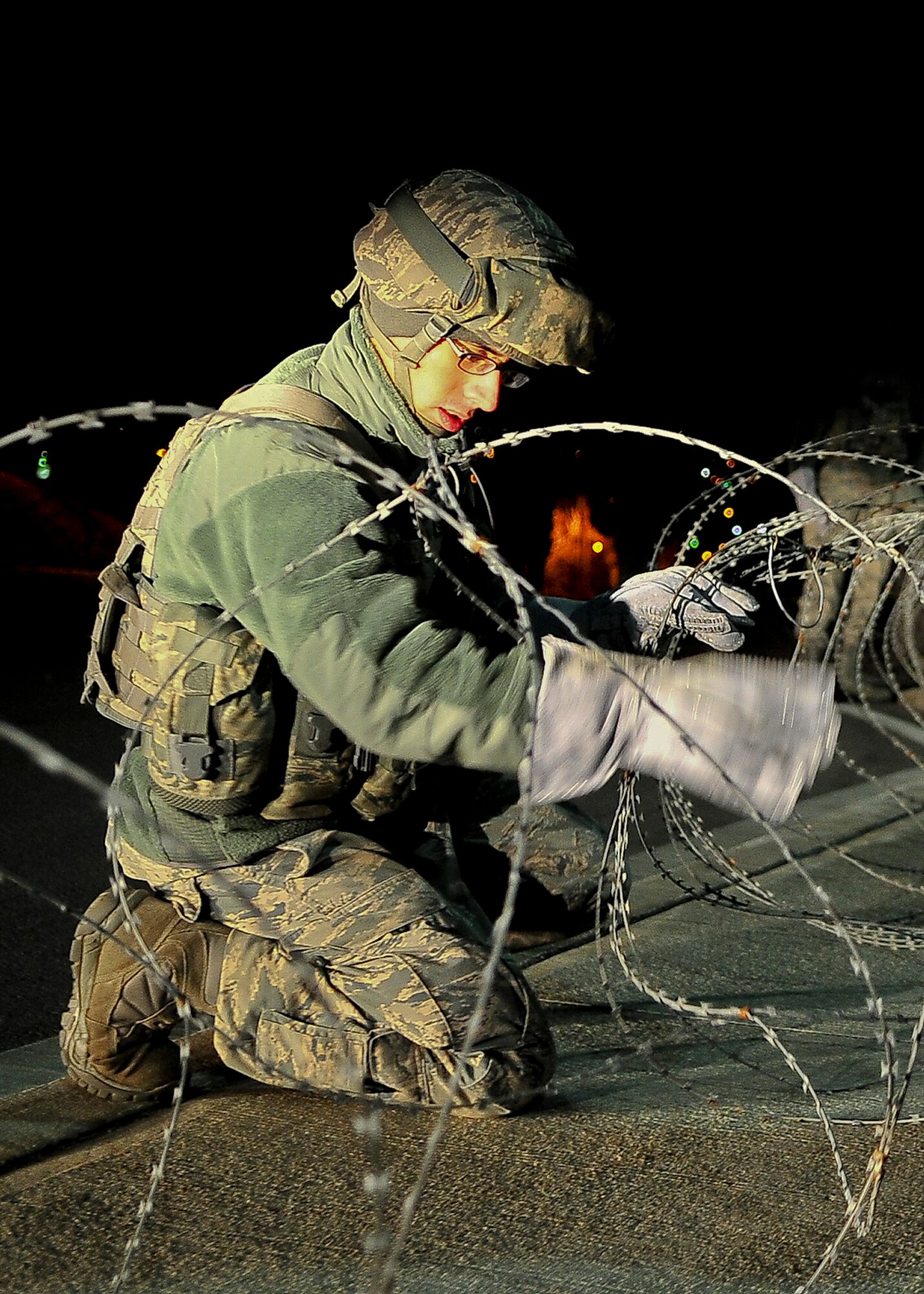 An Airman from the 51st Security Forces Squadron unwinds concertina wire around the perimeter of the base, March 18, 2012 during exercise Beverly-Midnight 12-01. Exercises like this test Osan Airmen's ability to survive and operate in a wartime environment and also tests their ability to plan and execute an exercise. (U.S. Air Force photo/Senior Airman Adam Grant)