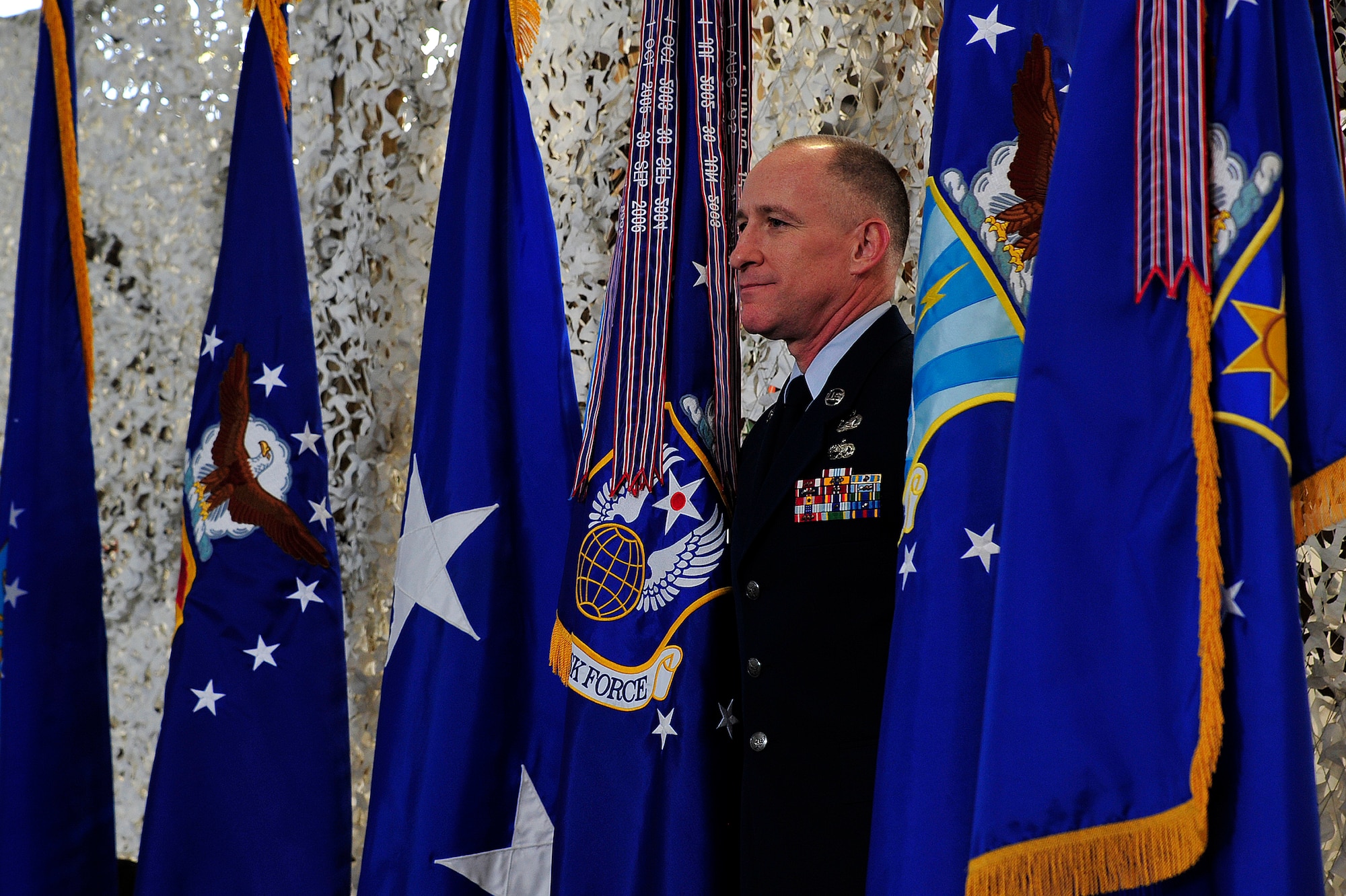 Chief Master Sgt. Earl Hannon, former 21st Expeditionary Mobility Task Force command chief, stands onstage with his unit's colors during the inactivation ceremony for the 21st EMTF at Joint Base McGuire-Dix-Lakehurst’s Global Reach Deployment Center March 19.  The inactivation of the 21st EMTF and administrative transfer of the its subordinate units, the 621st Contingency Response Wing and the 521st Air Mobility Operations Wing, to the EC is part of an Air Mobility Command restructuring initiative. (U.S. Air Force photo by Tech. Sgt. Parker Gyokeres/released)