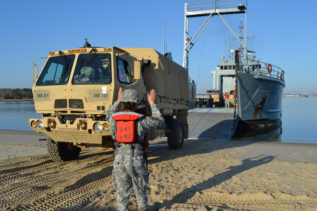 U.S. Army Spc. Hana Yi, 368th Seaport Operations Company, 11th Transportation Battalion, 7th Sustainment Brigade, ground guides a Light Medium Tactical Vehicle onto an Army Landing Craft Utility Mar. 14. The 2nd Platoon of 368th SOC trained in multi-modal transportation operations by convoying from Fort Story to Joint Expeditionary Base Little Creek, where the Soldiers loaded rolling stock onto the LCU and sailed to 3rd Port at Fort Eustis. (U.S. Army photo by 1st Lt. Andrea Whitaker/Released)