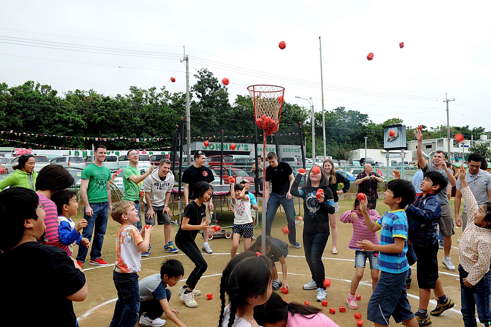 U.S. service members and children from Chatan Town's Busy Bee School play tamaire during a friendship day on Okinawa, March 17, 2012. The goal of the game is to stand outside a set of circles and toss as many bean bags as possible into a basket standing seven feet tall. (U.S. Air Force photo by Airman 1st Class Brooke P. Beers/Released)