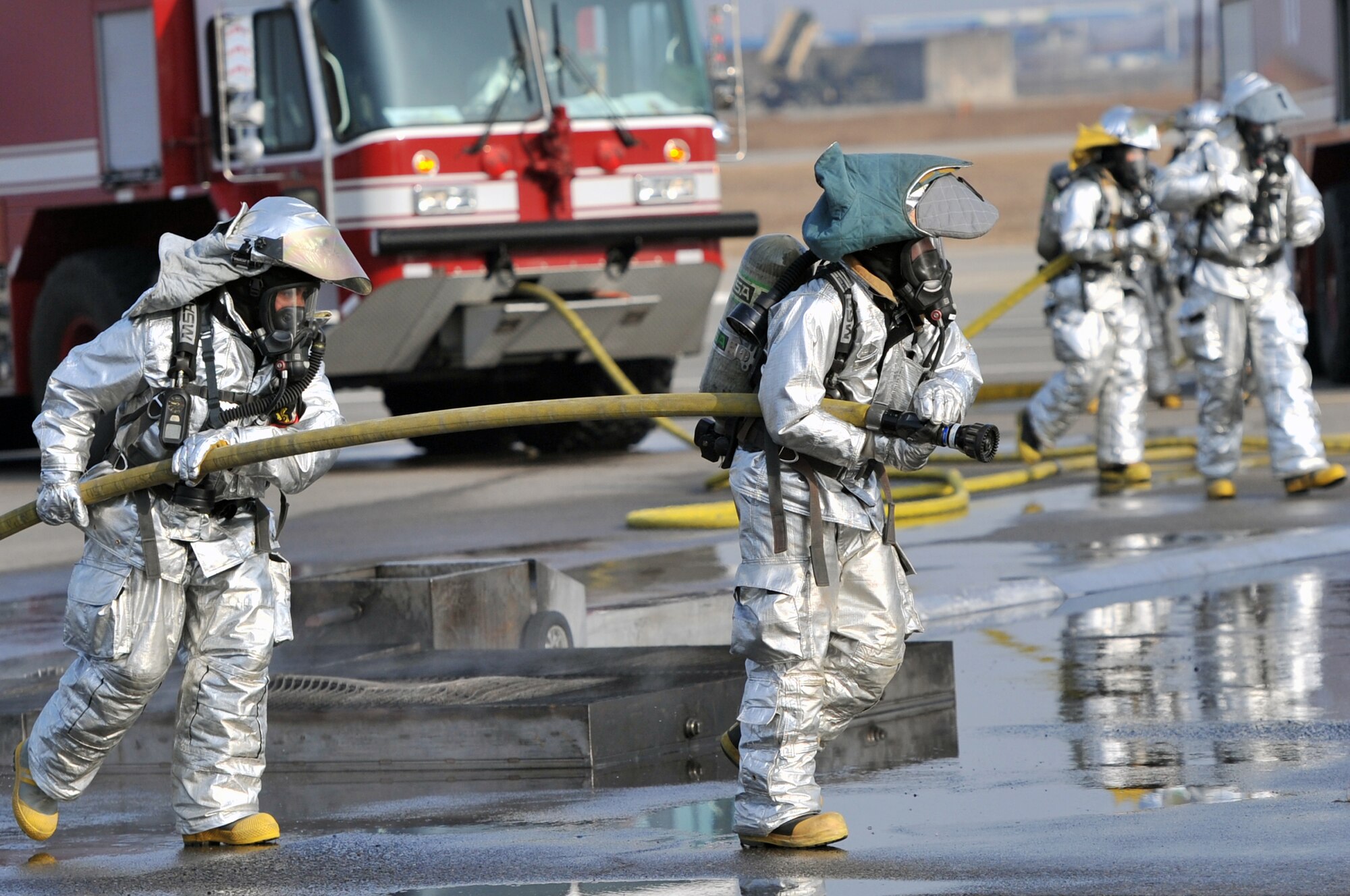 Firefighters from the 51st Civil Engineer Squadron pull water hoses toward a fire during operational readiness exercise Beverly Midnight 12-01 at Osan Air Base, March 19, 2012. The scenarios test Team Osan’s ability to defend the base and conduct daily operations during a heightened state of readiness. (U.S. Air Force photo/Staff Sgt. Craig R. Cisek)
