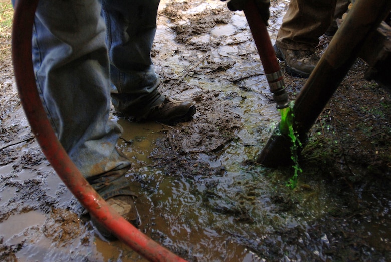 The Baltimore District drill crew inserts environmentally-safe green-yellow dye ine into the drill casing to test seepage paths downstream of the Saddle Dam at Center Hill Lake March 14, 2012. 