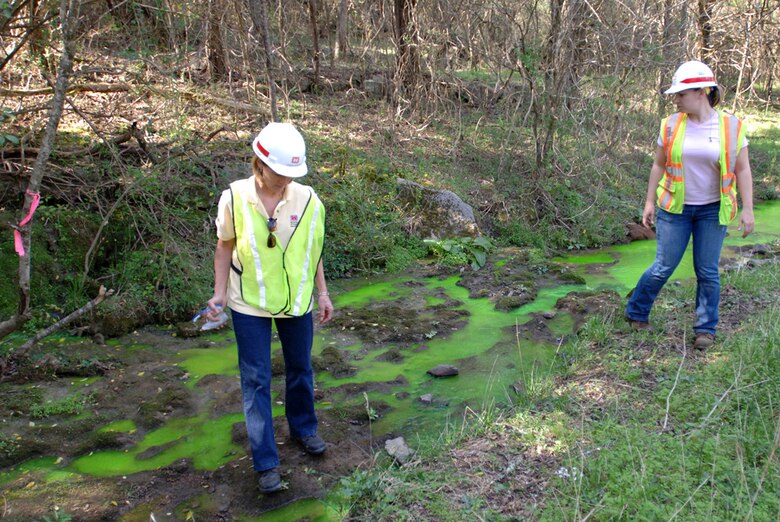 Project Manager Linda Adcock (left) and Geologist Sarah Mackey, U.S. Army Corps of Engineers Nashville District, mark a location where environmentally-safe green-yellow dye has exited from a rock formation indicating where seepage is making its way from the drill site. 