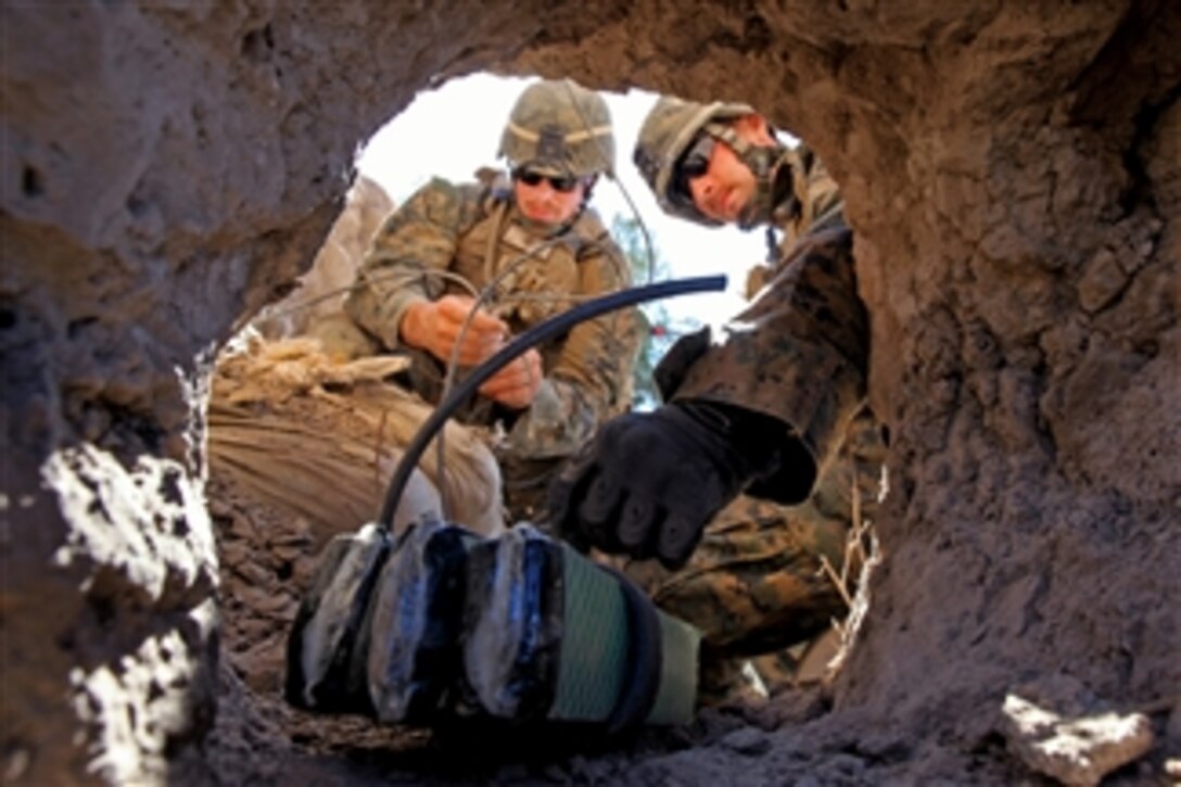 U.S. Marine Corps Lance Cpl. Benjamin Cool (left) ties a detonation cord as Lance Cpl. Josh Czerepka places several blocks of explosives into an insurgent firing position at a location in Afghanistan on March 5, 2012.  Cool and Czerepka are combat engineers assigned to the 1st Battalion, 8th Marine Regiment.  