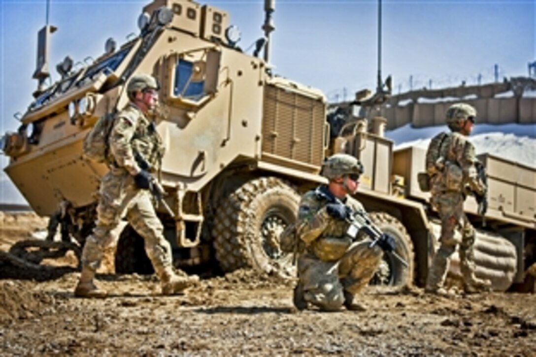 U.S. Army Spc. Tylor Calhoun, kneeling, provides security while fellow soldiers work to recover their heavy expanded mobility tactical truck wrecker from thick mud during a clearing operation near Combat Outpost Deh Yak in Afghanistan's Ghazni province, March 6, 2012. Calhoun is assigned to Company C, 1st Battalion, 2nd Infantry Regiment. U.S. and Afghan troops plan to disrupt insurgent movements into and through the area ahead of the spring fighting season.