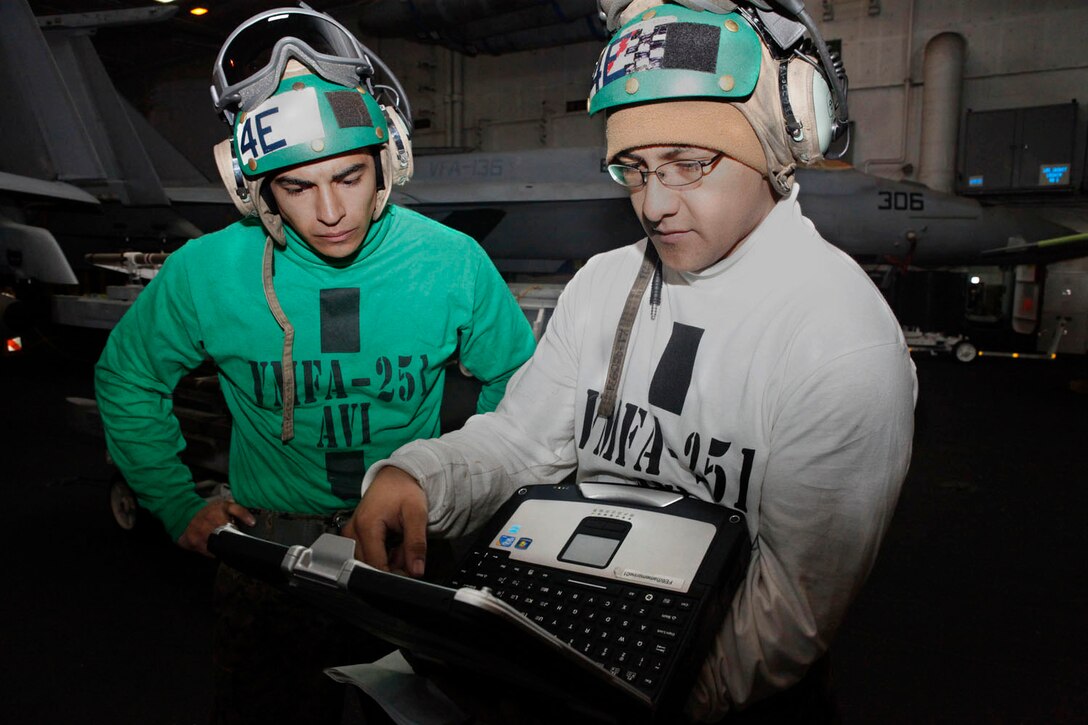 Lance Cpl. Joshua Ochoa, left, and Cpl. Victor Castellanos, Marine Fighter Attack Squadron 251 avionics technicians, review a circuit board diagram while aboard aircraft carrier USS Enterprise, March 19. The laptops allow the Marines to download various diagrams to increase job proficiency.