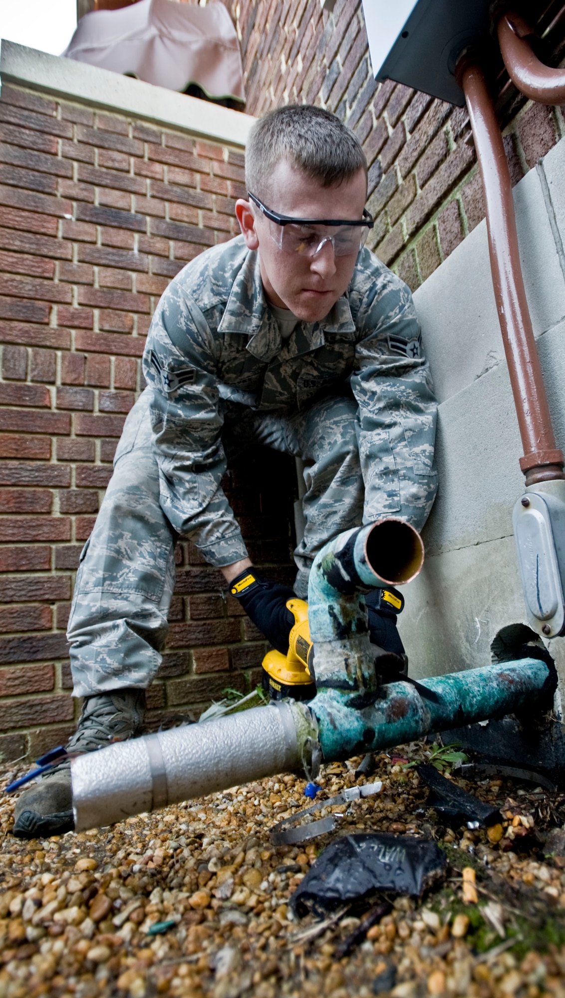 U.S. Air Force Airman 1st Class William Davey, 633rd Civil Engineer Squadron heating, ventilation and air conditioning apprentice, saws through a chill water line March 19, 2012, at Langley Air Force Base, Va. The outer water lines are also replaced, expanding the service life of the new chiller. (U.S. Air Force photo by Senior Airman Stephanie Rubi/Released)