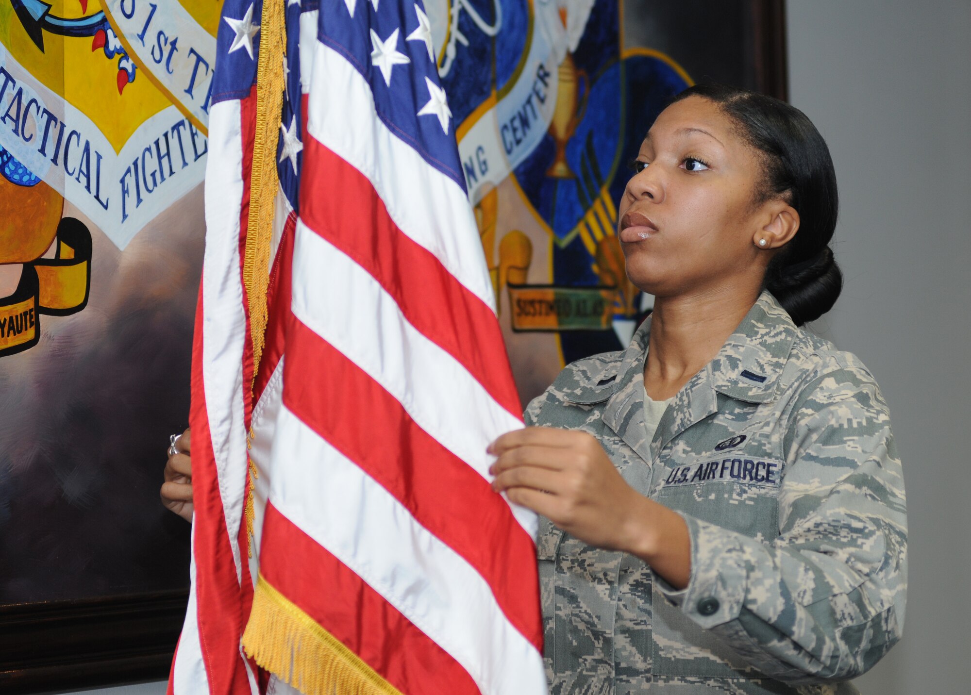 First Lt. Diaundra Davis, 81st Training Wing protocol chief, adjusts the United States flag so that it is facing toward the audience March 16, 2012, Keesler Air Force Base, Miss.  The protocol office is responsible for assuring customs and courtesies are followed during events to include flag placement and seating organization.  (U.S. Air Force photo by Kemberly Groue)