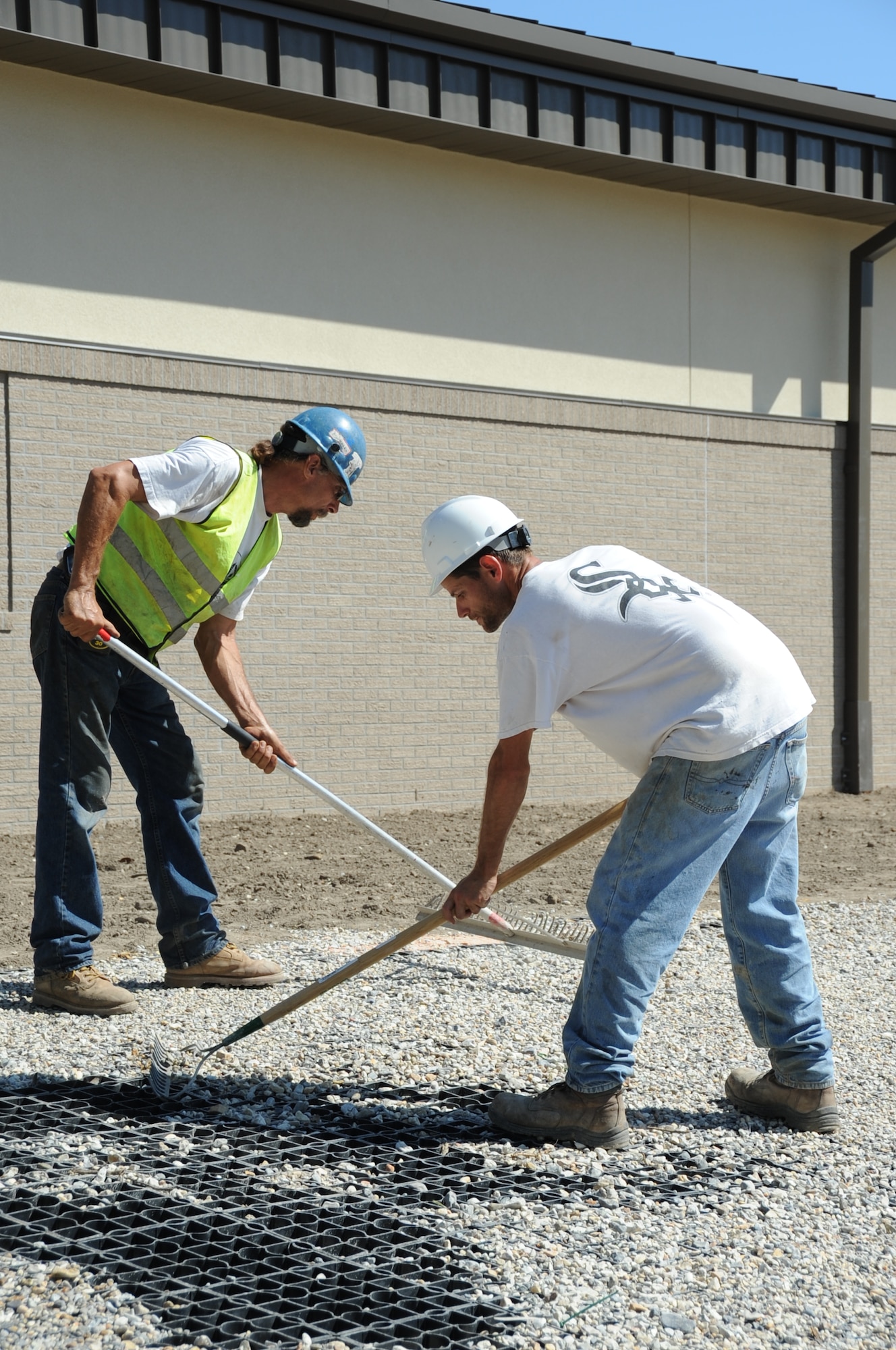 Steve Howard and Kevin Gary, laborers for Bulldog Construction, spread rock on the stable grid used to absorb water outside of the Keesler Indoor Firing Range at Keesler Air Force Base, Miss., March 15, 2012.   The 81st Security Forces Squadron and other base personnel will use the indoor facility for weapons training and qualifications. The facility is approximately 90 percent complete.  (U.S. Air Force photo by Kemberly Groue)