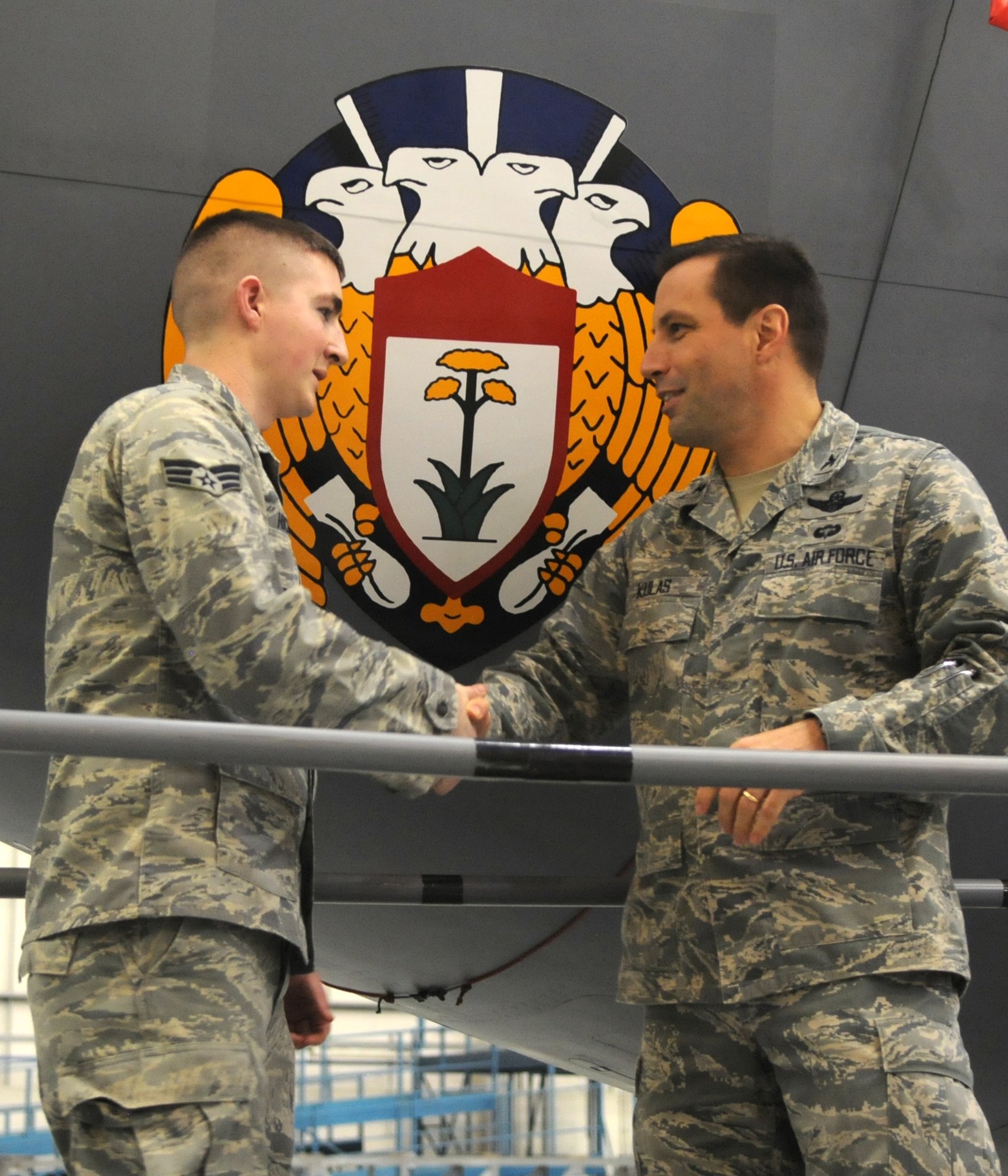 RAF MILDENHALL, England – Col. Christopher Kulas, 100th Air Refueling Wing commander, presents a coin to Senior Airman William Hickey, 100th Maintenance Squadron, during a small ceremony March 14, 2012. Kulas and Hickey worked together to place the historic emblem of the 100th Bomb Group – the 100th ARW’s World War II predecessor – to the nose of KC-135 Stratotanker 58-0100. The emblem was first approved in March 1944, when the 100th BG was flying B-17s out of RAF Thorpe Abbots over Nazi Germany. (U.S. Air Force photo by Staff Sgt. Austin M. May)