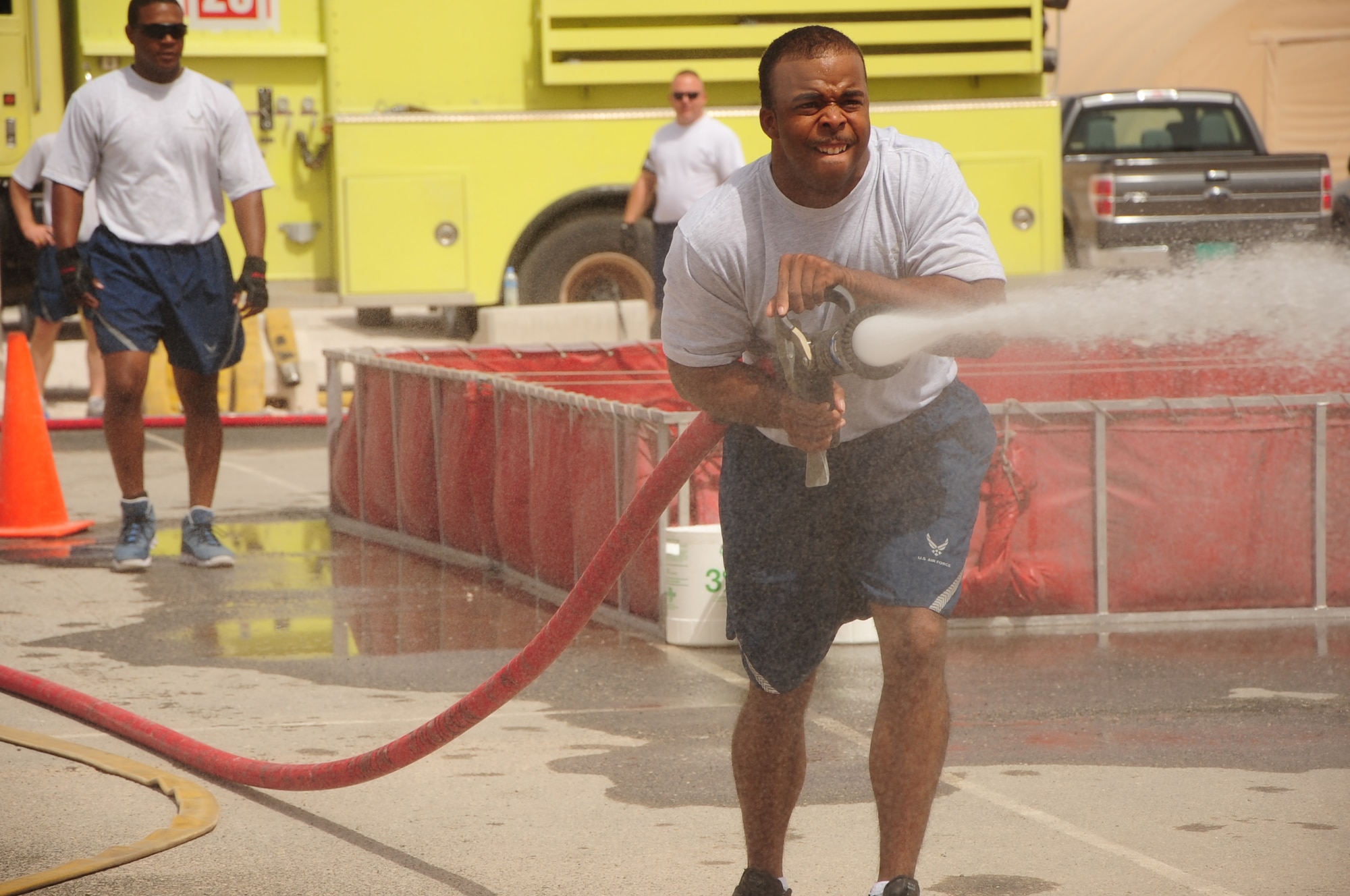 Senior Airman Marcus Dennis, 379th Air Expeditionary Wing escort flight specialist, sprays a fire hose at one of the stations during the Installation Fire Muster Competition March 17, 2012. The muster was organized by the Fire Department to bring the installation together and promote teamwork through friendly competition. The fire muster builds camaraderie while promoting fire prevention awareness around the base. (U.S. Air Force photo/Senior Airman Michael Charles)