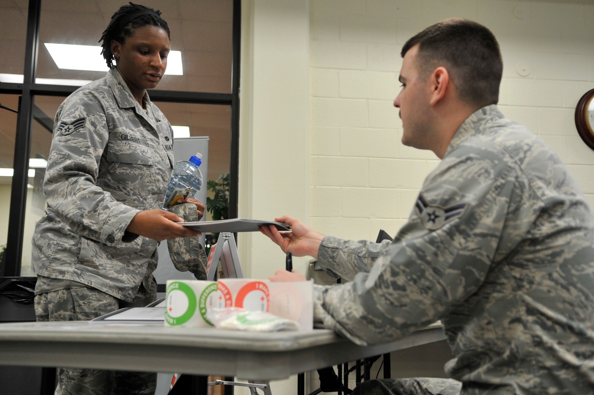 U.S. Air Force Senior Airman Vinetra Gilbert, 20th Component Maintenance Squadron Electronic Warfare Systems member, receives a folder from U.S. Air Force Airman 1st class, 20th Component Maintenance Squadron electronic warfare systems specialist, at the Community Center at Shaw Air Force Base, S.C., Mar. 14, 2012. Gilbert was preparing to give blood at the Wing Blood Drive. (U.S. Air Force photo by Airman Nicole Sikorski/Released) 