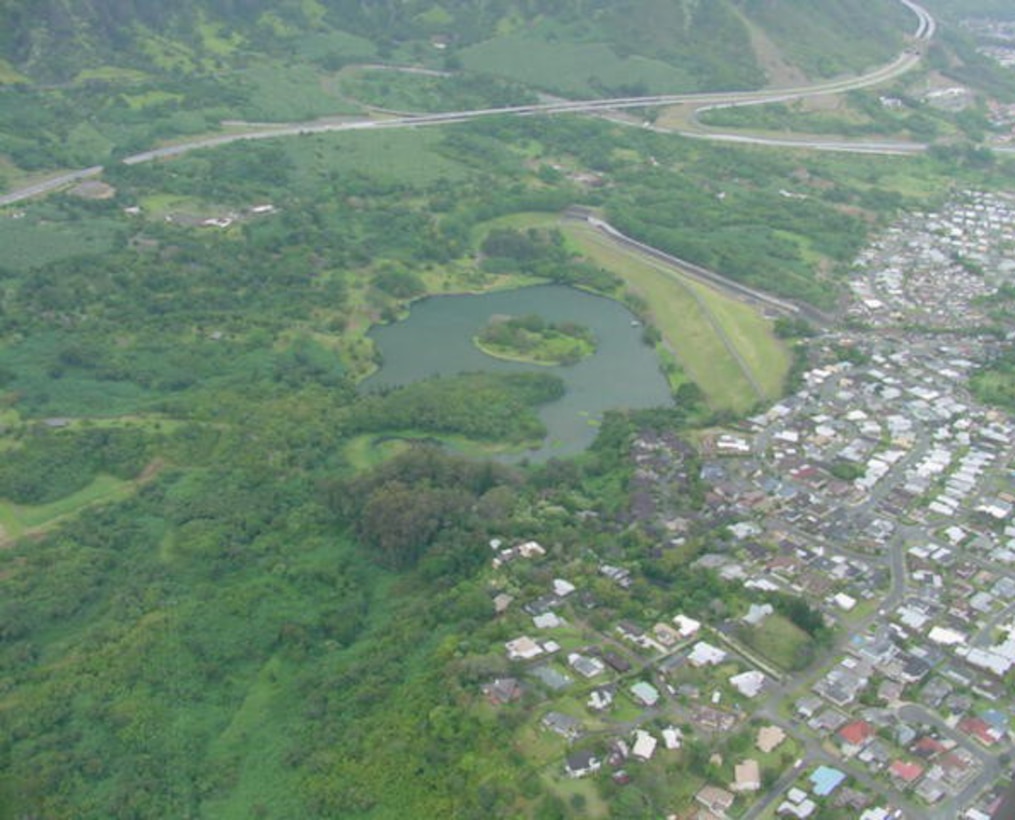Aerial photograph of the Kaneohe-Kailua Area environs and the flood control project. The project consists of a dam and reservoir on Kamooalii Stream, channel improvements at the mouth of Kaneohe Stream, and an allied public recreation park with fish and wildlife enhancement features. The park is named Hoomaluhia - Place of Peace. The Corps-constructed project was completed in July 1980. 
