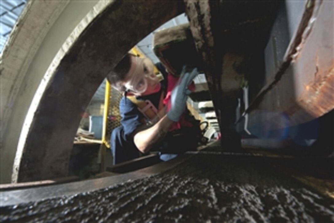 U.S. Navy Petty Officer Jason Garcia applies grease to hinges while performing maintenance on a weapons elevator aboard the USS Carl Vinson under way in the Arabian Sea, March 17, 2012. Garcia is an aviation ordnanceman assigned to the weapons department.