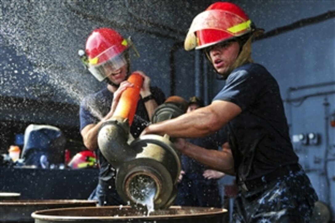 U.S. Navy Petty Officer 2nd Class Adam Mostafa and Petty Officer 3rd Class Clarence Thompkins conduct dewatering during the "Damage Control Olympics", an event aboard the aircraft carrier USS Carl Vinson in the Arabian Sea, March 16, 2012. The Carl Vinson and Carrier Air Wing 17 are deployed to the U.S. 5th Fleet area of responsibility.