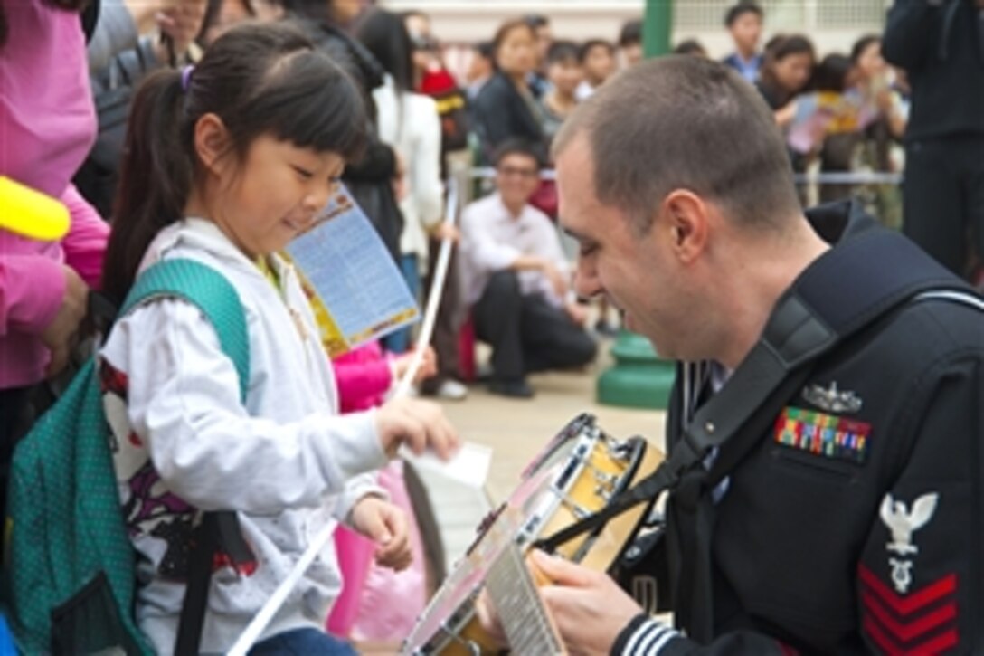 U.S. Navy Petty Officer 1st Class Brian Nefferdorf teaches a girl how to strum the banjo while his band performs in front of about 800 people at Hong Kong Disneyland in Hong Kong, March 19, 2012 . Sailors from the U.S. 7th Fleet flagship USS Blue Ridge are in Hong Kong for a port visit. Nefferdorf plays with the Pacific Ambassaors, the U.S. 7th Fleet's band.
