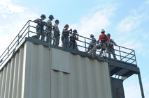 Airmen watch instructor Joseph Gomos, prepare to rappel off the burn tower during a Department of Defense Rescue Technician Course on Seymour Johnson Air Force Base, N.C., March 20, 2012. Gomos is one of nine members attached to the DOD Fire Academy mobile unit, which travels to various military installations teaching fire rescue techniques. Gomos, DOD Fire Academy instructor from Goodfellow Air Force Base, Texas, hails from Bancroft, Mo. (U.S. Air Force photo/Airman 1st Class Aubrey Robinson/Released)