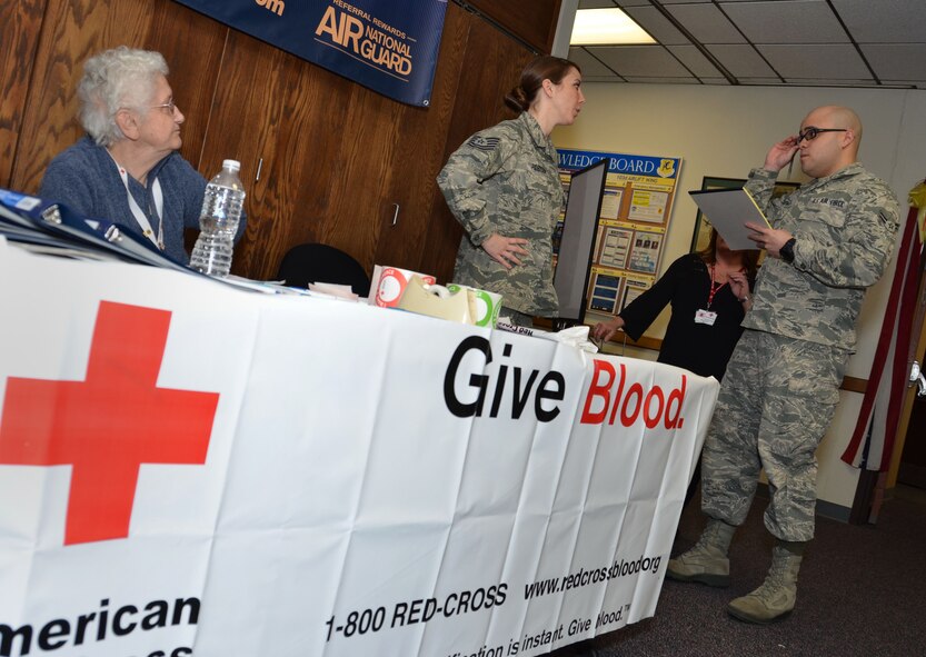 Tech. Sgt. Amy Robison from the 103rd Maintenance Squadron discusses the blood drive that was held at Bradley Air National Guard Base, East Granby, Conn. with Airman 1st Class Emmanuel Santiago, 103rd Public Affairs, March 3, 2012. The event was put together by Robison and the Charter Oak branch of the American Red Cross that is comprised of volunteers like Louise Brule, seen seated at the table.  (U.S. Air Force photo by Tech. Sgt. Joshua Mead)