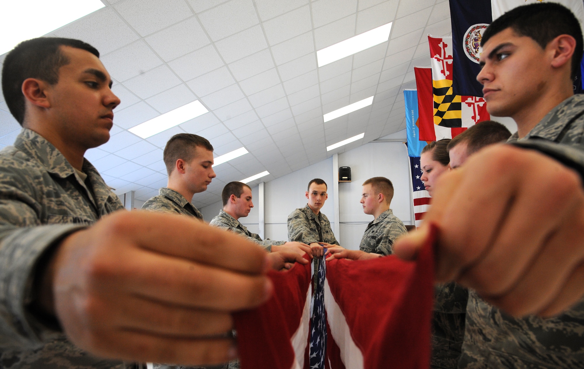 Senior Airman Benjamin Collins, center, places his right fist down the center in order to train new members of the Grand Forks Air Force Base Honor Guard the proper spacing required during one part of a six-man flag folding routine, Mar. 8, 2012 at the Honor Guard training facility at Grand Forks AFB, N.D.  A U.S. flag is customarily folded by six honor guardsmen while rending military honors during a funeral service for a deceased Air Force retiree of active duty member.  Collins has participated in more than 150 ceremonies. (U.S. Air Force photo/Airman 1st Class Xavier Navarro)