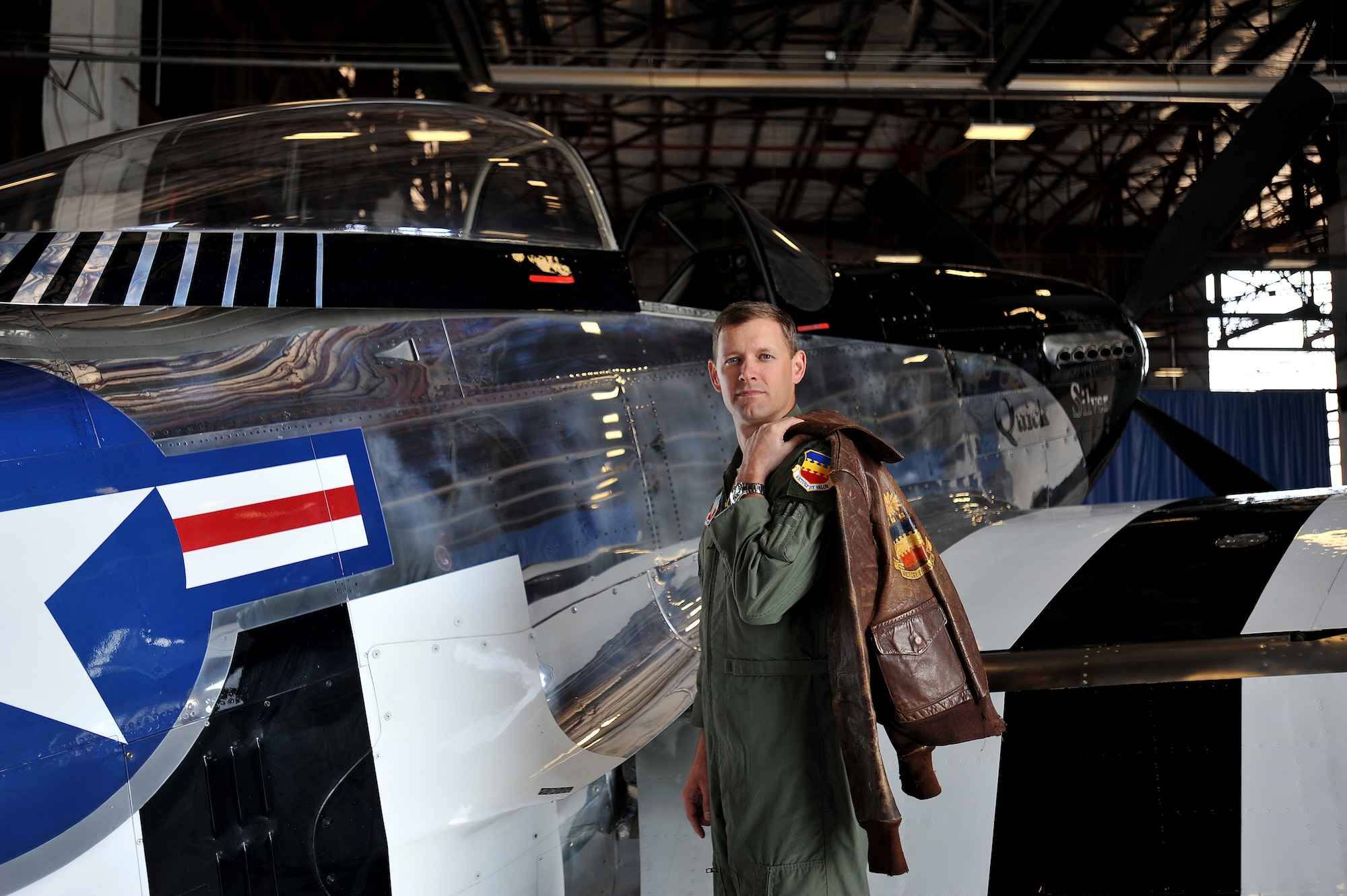 U.S. Air Force Lt. Col Scott Walker, Shaw Air Expo director, poses for a photo in front of a P-51 Mustang while holding an old 20th Fighter Wing flight jacket, Shaw Air Force Base, S.C., March 19, 2012. The P-51 Mustang "Quick Silver" was restored more than 13 years ago by father and son Bill and Scott Yoak. Yoak's P-51 Mustang will be one of the many aircraft that will perform during the upcoming Shaw Air Expo, May 5-6. (U.S. Air Force photo by Senior Airman Kenny Holston/Released)

