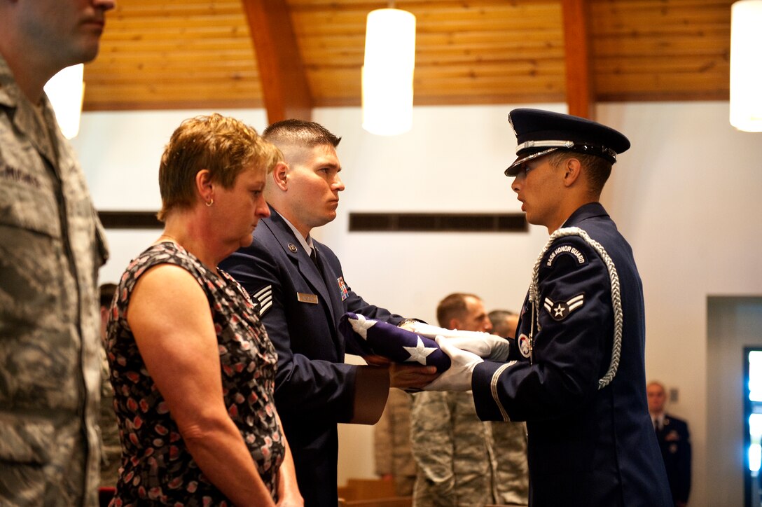 A member of the Hurlburt Field Honor Guard passes an American flag to Staff Sgt. Robert Calhoun, a military working dog handler from the 1st Special Operations Security Forces Squadron, during a memorial ceremony at the base chapel on Hurlburt Field, Fla., March 16, 2012. Calhoun was the last handler for Rony, an MWD, who was euthanized March 7, 2012 after suffering from cancer and internal bleeding. (U.S. Air Force photo/Airman 1st Class Christopher Williams)(Released)