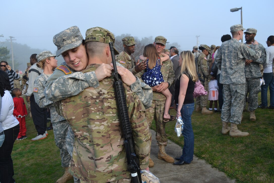U.S. Army Pvt. Nina Dominguez, Headquarters and Headquarters Detachment, 11th Transportation Battalion, hugs Pfc. Tracey Spoerer, 119th Inland Cargo Transfer Company, 11th Trans. Bn., outside of the Joint Expeditionary Base-Fort Story Gym after a deployment ceremony Tuesday. In the background, Spc. Joshua Byrd (left), 119th ICTC, 11th Trans. Bn., comforts Grace Coleman, 5, while she hugs her father, Spc. Sean Coleman (center), 119th ICTC, 11th Trans. Bn., while her mother, Jillian Coleman (right), looks on. The 119th ICTC deployed to Afghanistan for 12 months to provide logistical support to deployed forces by overseeing a Central Receiving and Shipping Point. (U.S. Army photo by 1st Lt. Andrea Whitaker/Released)