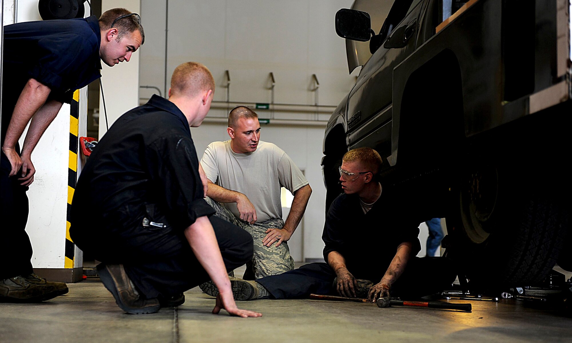 U.S. Air Force Senior Airman Craig Galvin, 18th Logistics Readiness Squadron vehicle maintenance journeyman (Far Right), talks with other mechanics while working on replacing a flex plate on Kadena Air Base, Japan, March 21, 2012. Galvin and the other Airmen of vehicle maintenance help keep Shogun Airmen mobile so the Kadena mission can be completed more efficiently. (U.S. Air Force photo by Airman 1st Class Brooke P. Beers/Released)