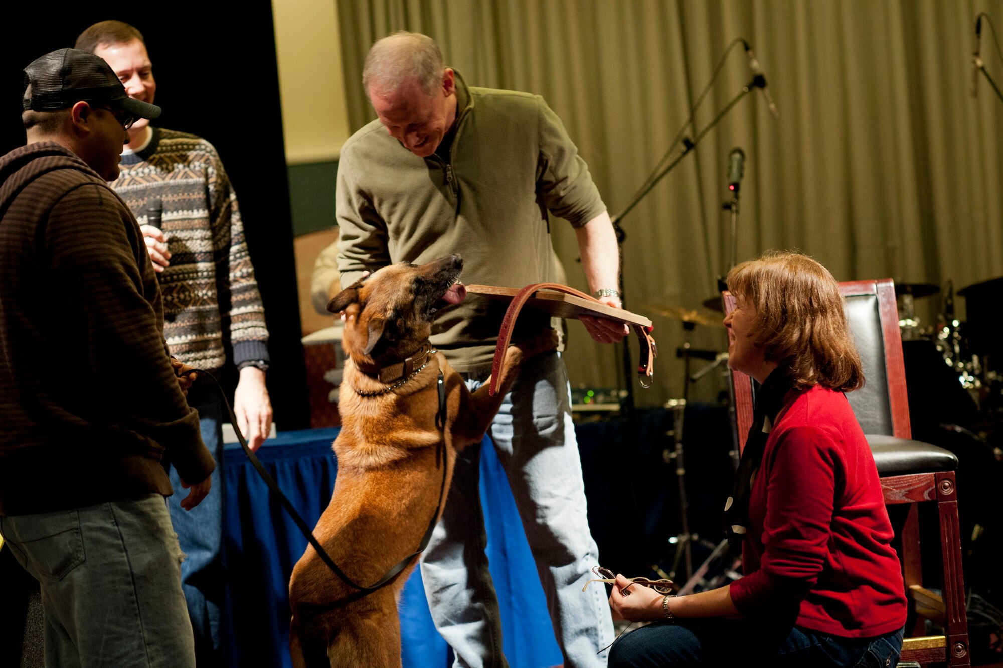 YOKOTA AIR BASE, Japan -- Tech. Sgt. Raymond Castro (left), 374th Security Forces Squadron military working dog section NCO in charge, presents Elra, a 374th SFS military working dog, to Col. Otto Feather (center), 374th Airlift Wing commander, during his going away party at Yokota Air Base, Japan, March 17, 2012. Feather and his wife, Nancy (right), tried to adopt Elra to accompany them in retirement, and the adoption had been approved that morning. This was the first time the Feathers found out they were able to adopt Elra. (U.S. Air Force photo/Staff Sgt. Samuel Morse)