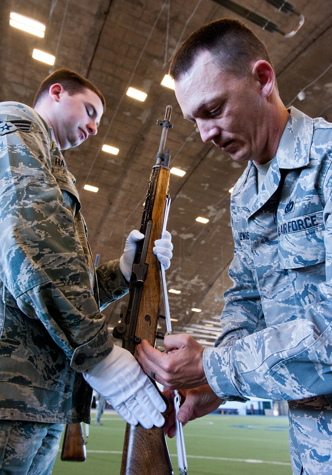 Tech. Sgt. Michael Lewis, Ellsworth Honor Guard NCO in charge, instructs honor guardsmen, Senior Airman Deryck Hazelton, 28th Maintenance Group knowledge operations manager, how to perfect his weapon handling technique during a funeral practice sequence in the Pride Hangar at Ellsworth Air Force Base, S.D., March 19, 2012. The honor guard continuously practices to ensure they can perform services with pinpoint accuracy. (U.S. Air Force photo by Airman 1st Class Kate Thornton/Released)