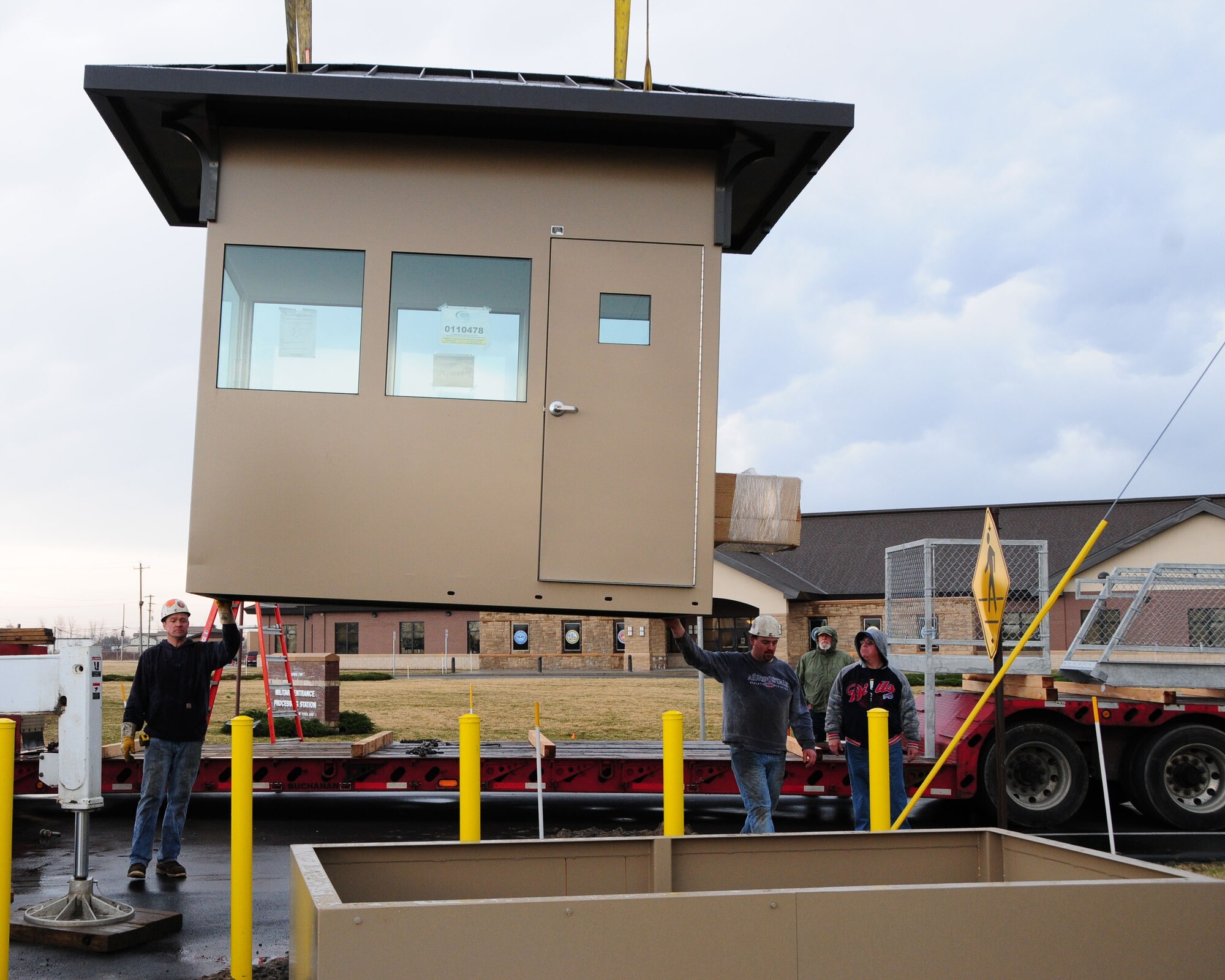 Workers guide the new Security Forces over watch booth into place near the main gate at Niagara Falls Air Reserve Station, NY on March 15, 2012. This new hardened facility will replace a guard booth which did not allow security forces a clear view of the main gate vehicle check. This new state of the art over watch has protective measures built into the booth to protect the guard on duty against hostile action, a higher vantage point and allows the individual to assist in deterring any unauthorized entry. (U.S. Air Force photo by Peter Borys)