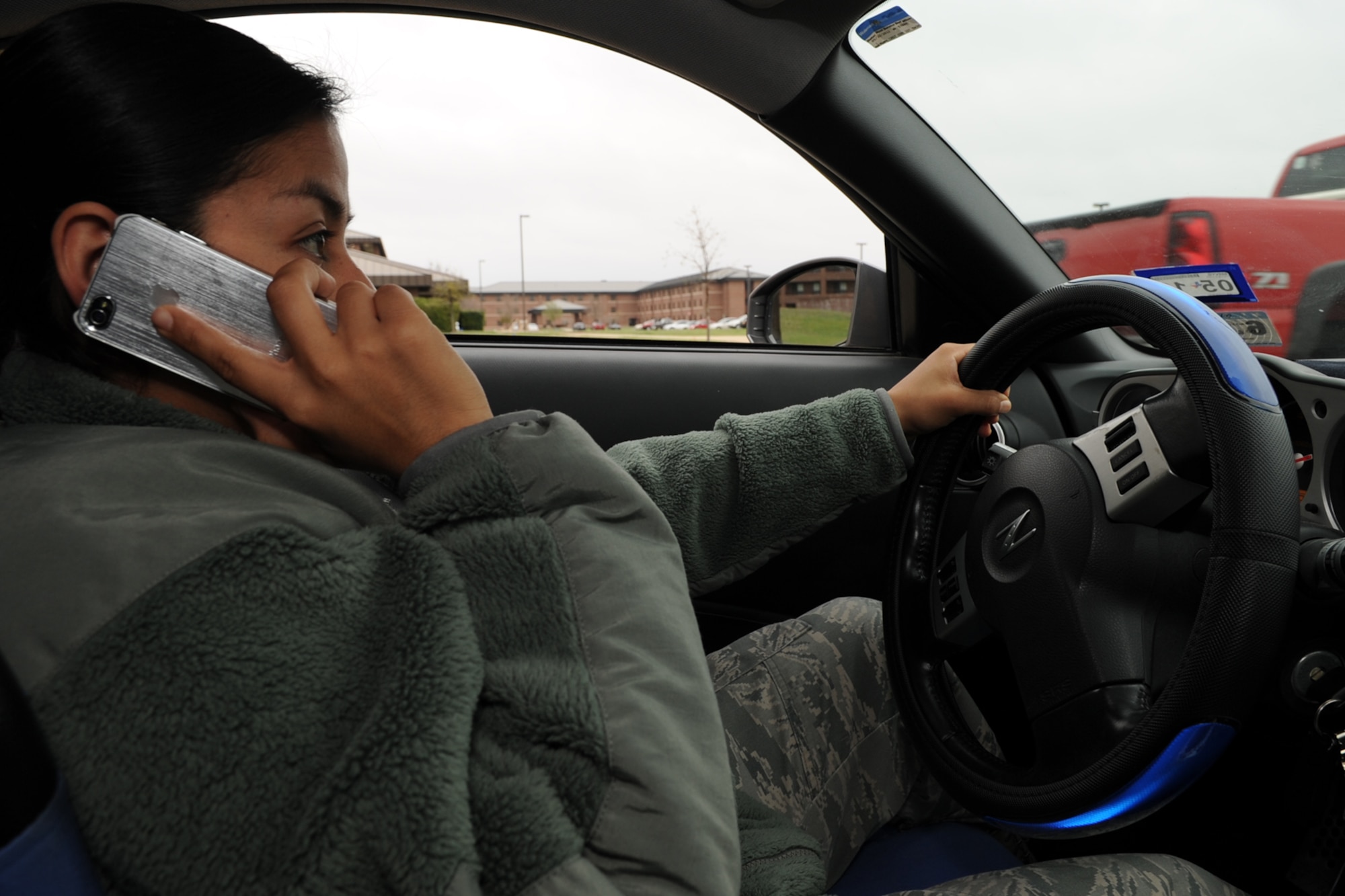 GOODFELLOW AIR FORCE BASE, Texas -- Senior Airman Nancy Foster, 17th Security Forces Squadron, imitates driving and talking on a cell phone without the proper use of hands free technology, March 14. According to AFI 36-2903 Dress and Personal Appearance of Air Force Personnel paragraph 6.3.3.1., use of a hands-free device is authorized while in uniform when operating a motor vehicle if local policy permits. (U.S. Air Force photo/Staff Sgt. Laura R. McFarlane)