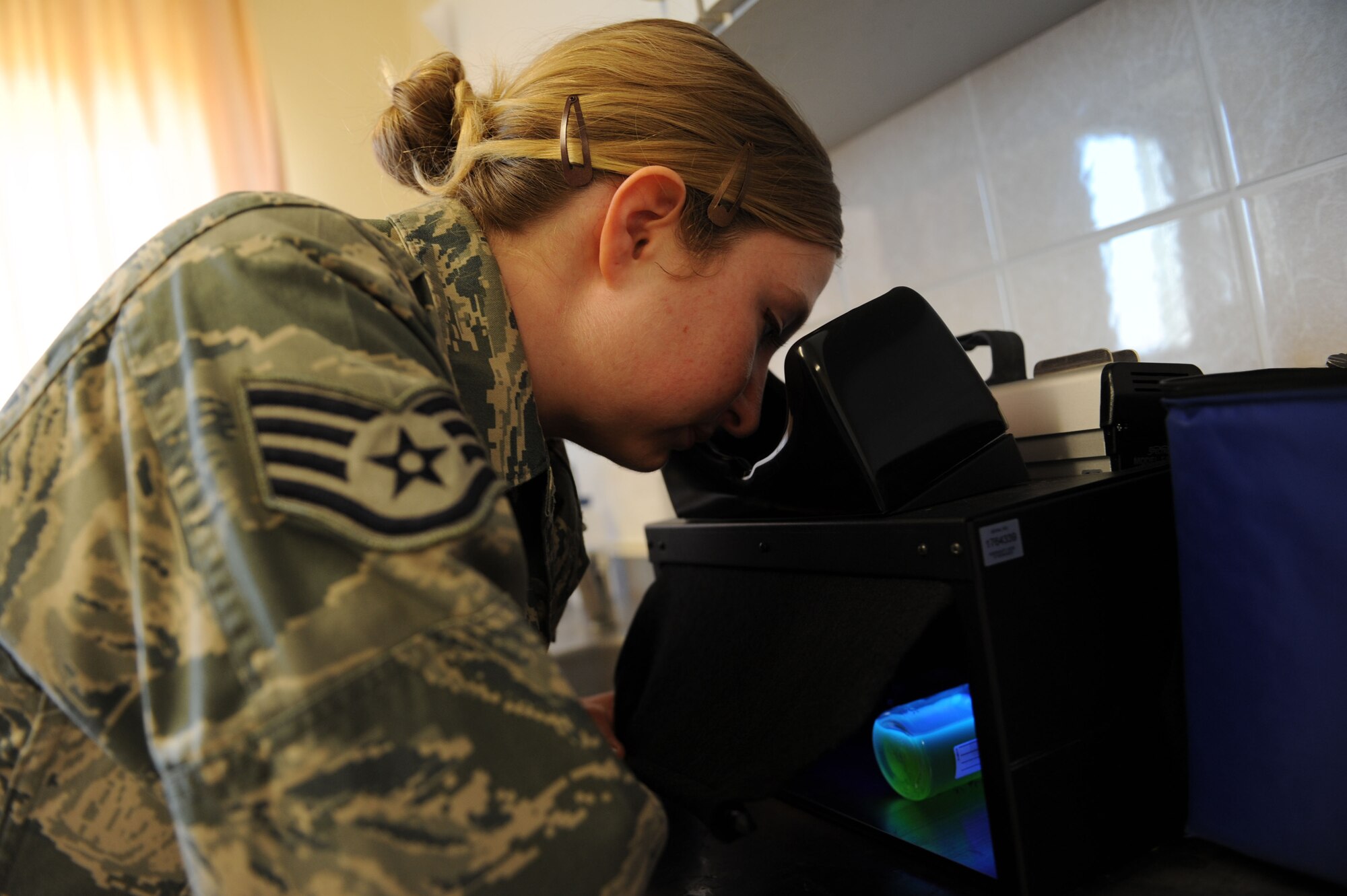SPANGDAHLEM AIR BASE, Germany – Staff Sgt. Eva Doty, 52nd Aerospace Medicine Squadron water protection program NCO in charge, uses a black light to check a water sample at Bldg. 175 here March 20 for florescence to ensure no harmful bacteria is in the base water system. Samples are taken at 21 different locations around base every month. The amount of samples taken per month is based on governing standards as well as the base population. The Airmen provide emergency response capability, monitor drinking water, assess chemical and noise hazards, and protect the environment against contamination from accidental releases of hazardous materials. (U.S. Air Force photo by Senior Airman Christopher Toon/Released)