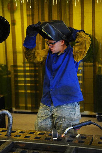 Airman 1st Class Brooke Goosen, 7th Equipment Maintenance Squadron, puts on protective gear before welding a foreign object damage stand March 20, 2012, at Dyess Air Force Base, Texas. The welding shop repairs damaged machinery, aircraft metal and various equipment. (U.S. Air Force photo by Airman 1st Class Cierra Bullock/Released)