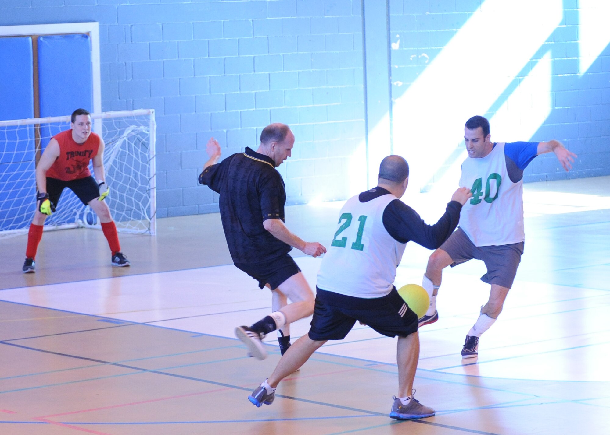 John Bourke, right, and Roger Vula, center, both with the 100th Operations Group team, attack the ball as Gary Butcher, in black, 100th Force Support Squadron, attempts to seize control during an intramural indoor soccer game at the Northside Fitness Center here March 20, 2012. The 100th FSS eased through to their third straight win by defeating the 100th OG 5-1. (U.S. Air Force photo/Tech. Sgt. Neal X. Joiner) 