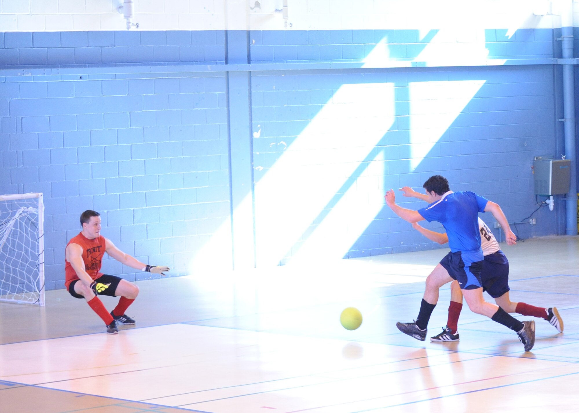 Bruce Richardson, in blue, 100th Force Support Squadron, attempts a goal as Steve Beaulieu, 100th Operations Group goalie, defends during an intramural indoor soccer game at the Northside Fitness Center here March 20, 2012. The 100th FSS eased through to their third straight win by defeating the 100th OG 5-1. (U.S. Air Force photo/Tech. Sgt. Neal X. Joiner) 