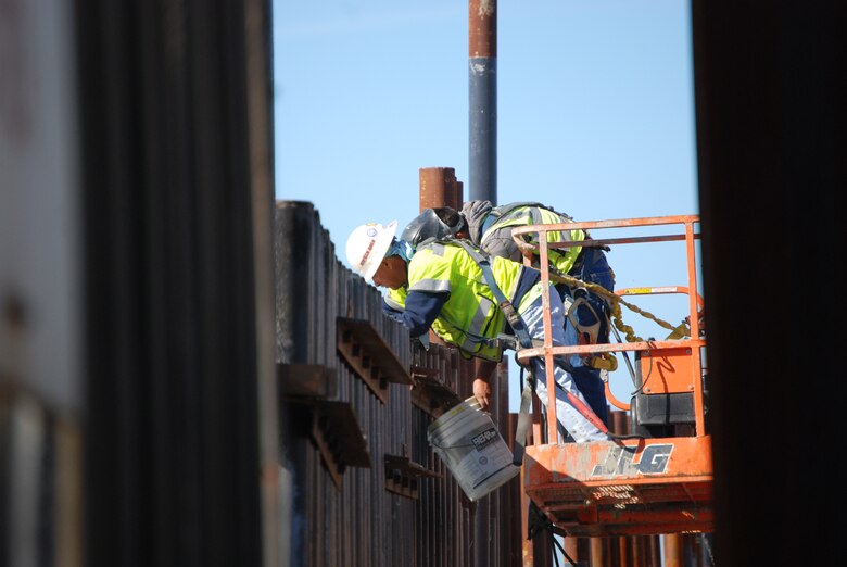 Construction workers connect templates to align pilings for the border fence being constructed in the surf zone near Imperial Beach, Calif.  The fence extends 300 feet into the Pacific Ocean.