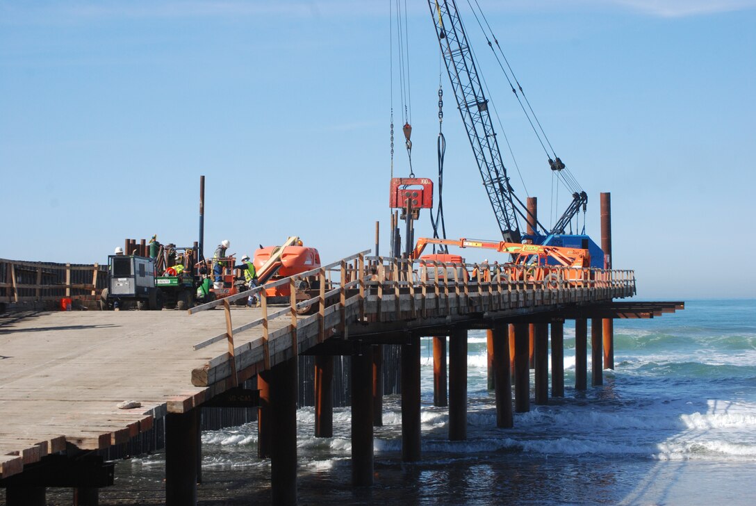 A crane and other construction equipment sit atop the temporary pier built to construct the westernmost segment of the border fence that separates Mexico and the United States. The pier enabled the contractor to overcome obstacles unique to working in a surf zone.