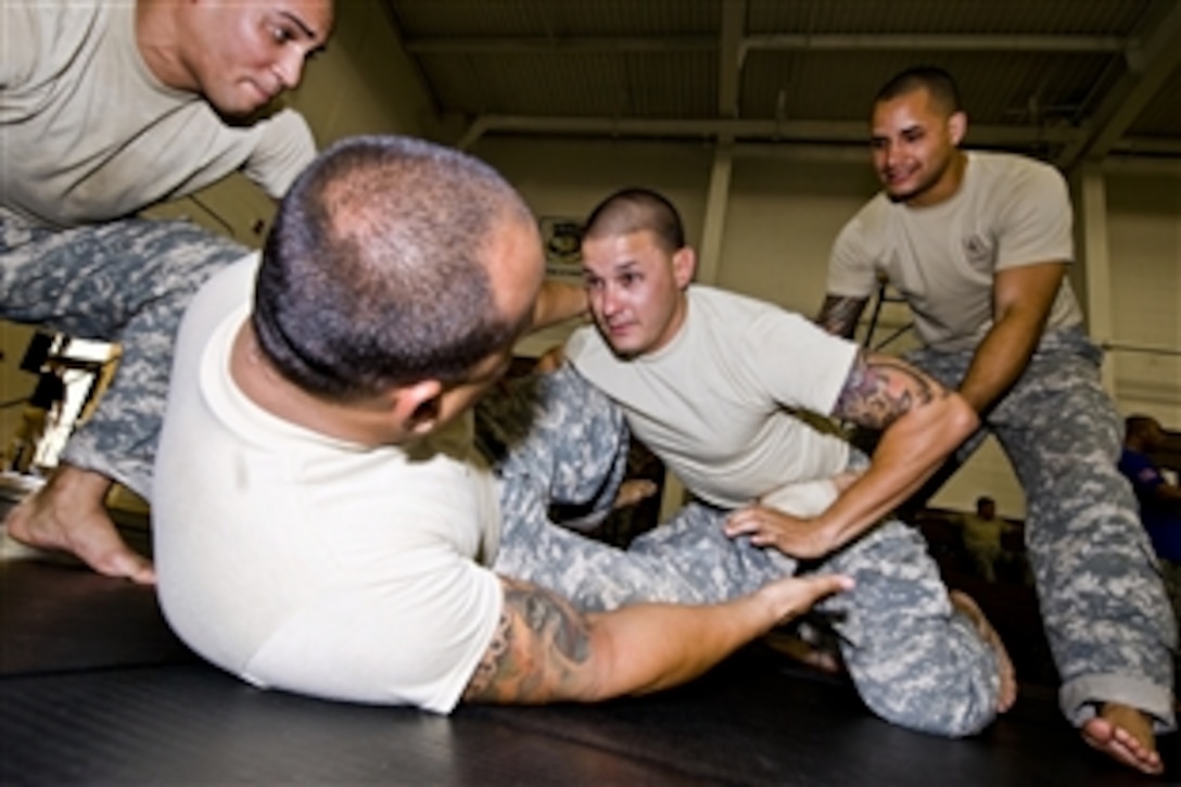 Army Spc. Ernesto Ventura works with combatives team members Sgt. Gregory Maldonado, Sgt. Juan Ortiz and Sgt. Angel Santiago, on his back, at the 2012 National Guard Combatives Tournament hosted by the Warrior Training Center on Fort Benning, Ga., March 17, 2012. Ventura is assigned to the Alaska National Guard and his combatives team members are assigned to the Puerto Rican National Guard. 