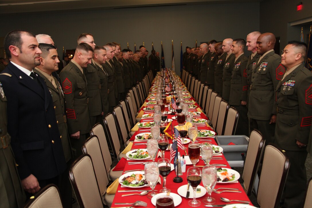 Marines of Center for Naval Aviation Technical Training take their seats at a Mess Night in Miller’s Landing, March 23. Some of them crack up when they realize one of their master sergeants will have to eat his meal from a “specially designed” chair.