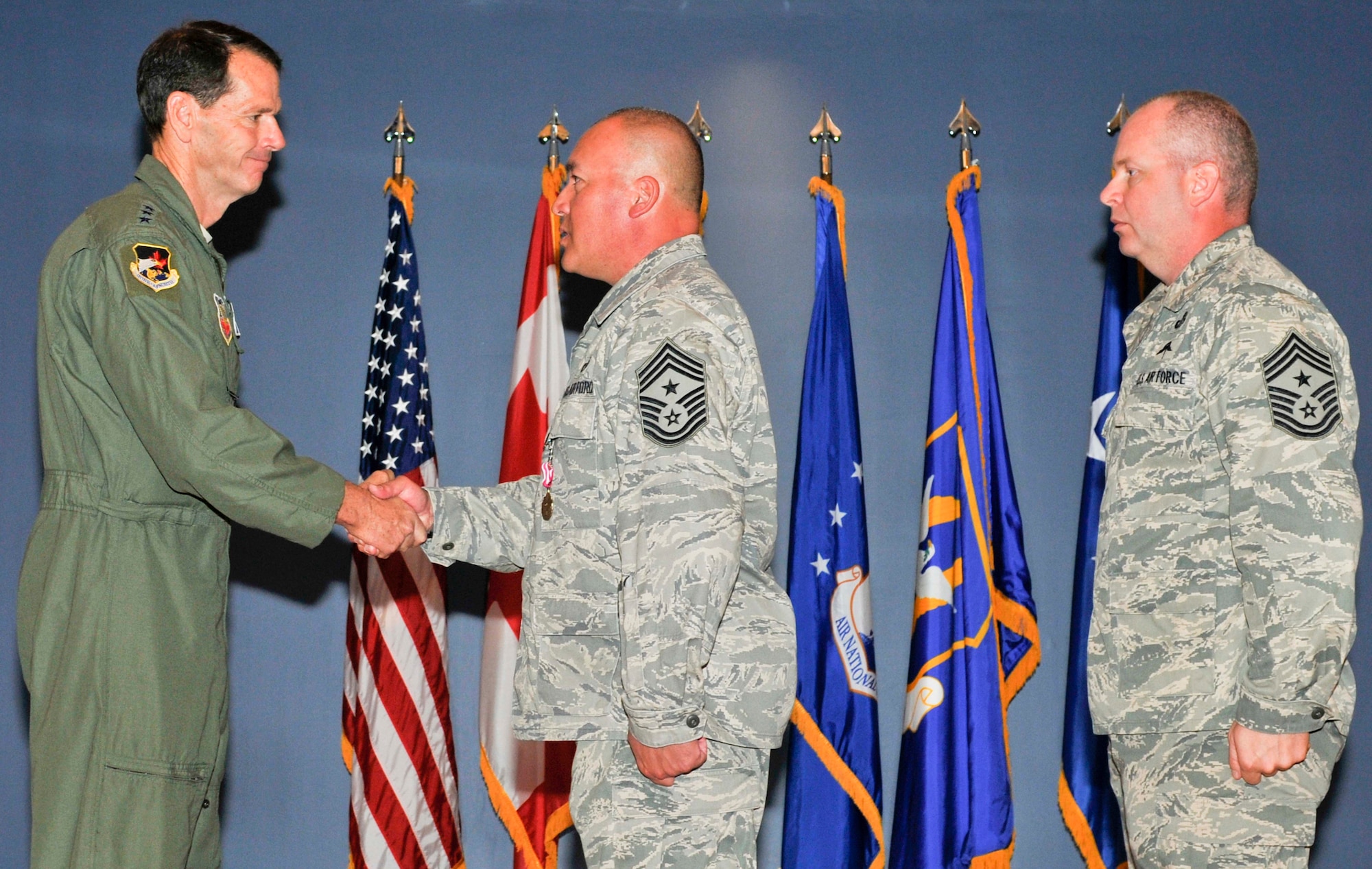 Chief Master Sgt. Mitchell Brush (center), the former Air Forces Northern command chief, passes his command chief coin to Lt. Gen. Sid Clarke, AFNORTH commander, during a transfer of authority ceremony at Tyndall Air Force Base, Fla., March 23. Chief Brush passed responsibility of the command’s enlisted force to Chief Master Sgt. Jim Hotaling (right). (U.S. Air Force photo by Susan Trahan) 