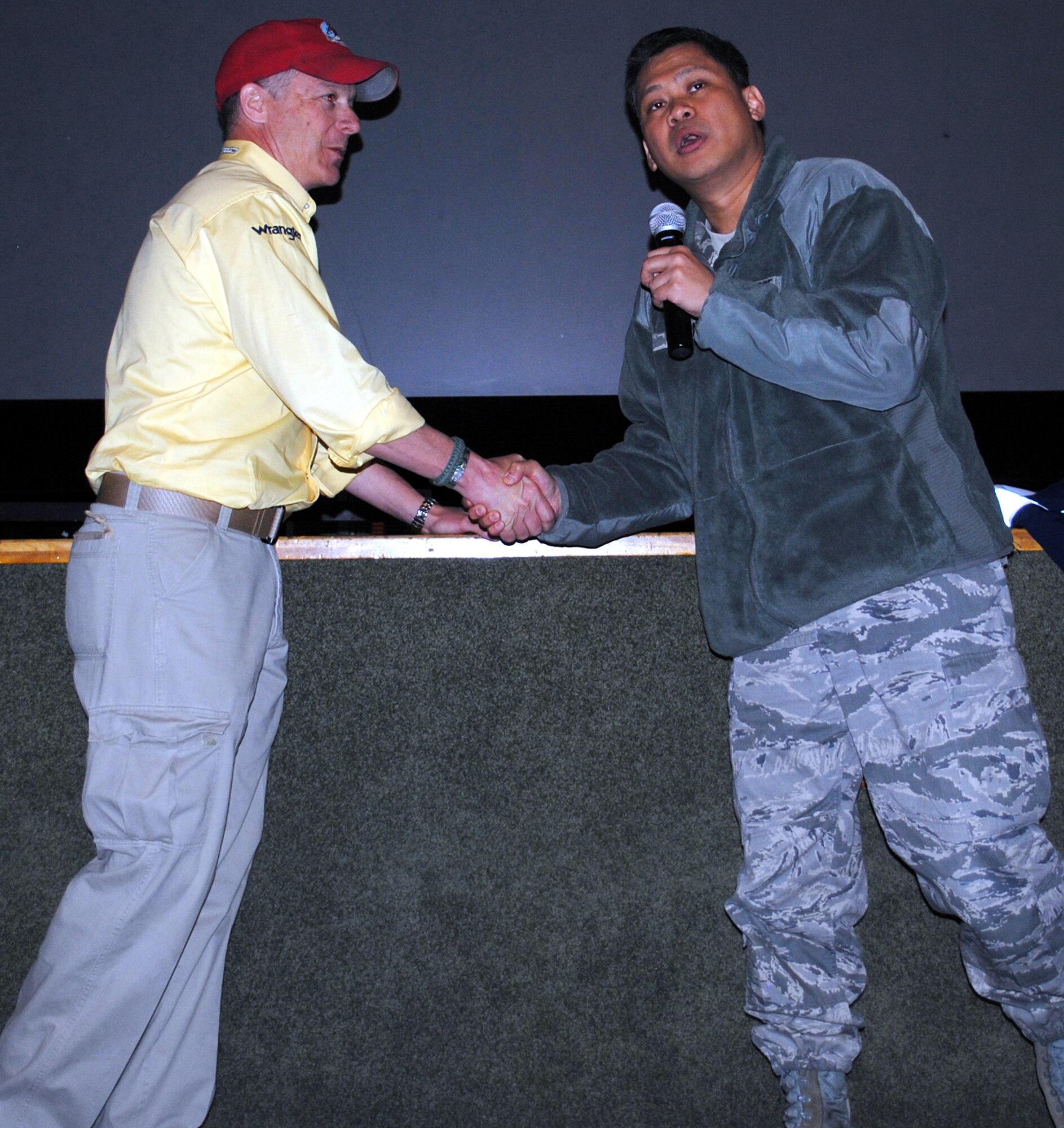 Col. H. B. Brual, 341st Missile Wing commander, coins Robi Powers, founder of the American300 Warrior Tours, following his presentation at the base Auditorium March 22.  (U.S. Air Force photo/Airman 1st Class Cortney Paxton)