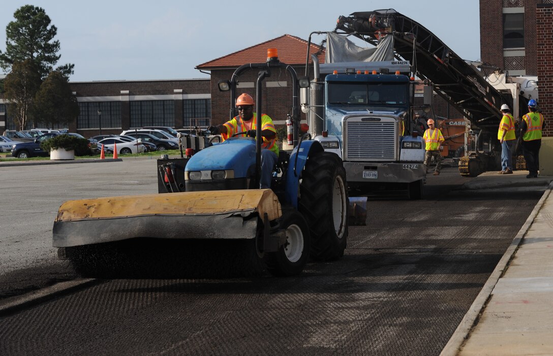 Construction workers mill and sweep asphalt at the Air Combat Command Fitness Center March 22, 2012, at Langley Air Force Base, Va. The workers will recycle the asphalt and use it to repave the parking lot. (U.S. Air Force photo by Airman 1st Class Teresa Cleveland/Released)