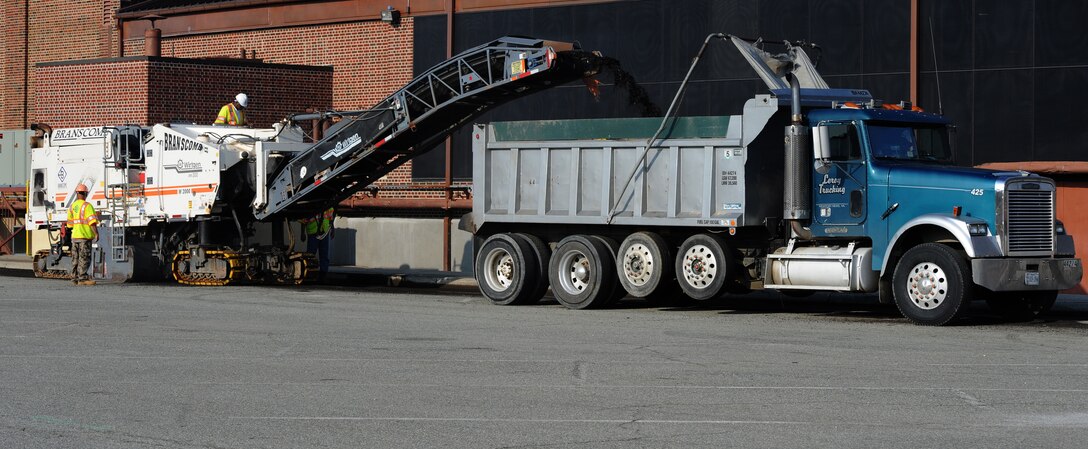 Construction workers use a milling machine to grind asphalt at the Air Combat Command Fitness Center at Langley Air Force Base, Va., March 22, 2012. Langley personnel should expect changes to traffic and parking patterns near the gym due to the construction. (U.S. Air Force photo by Airman 1st Class Teresa Cleveland/Released)