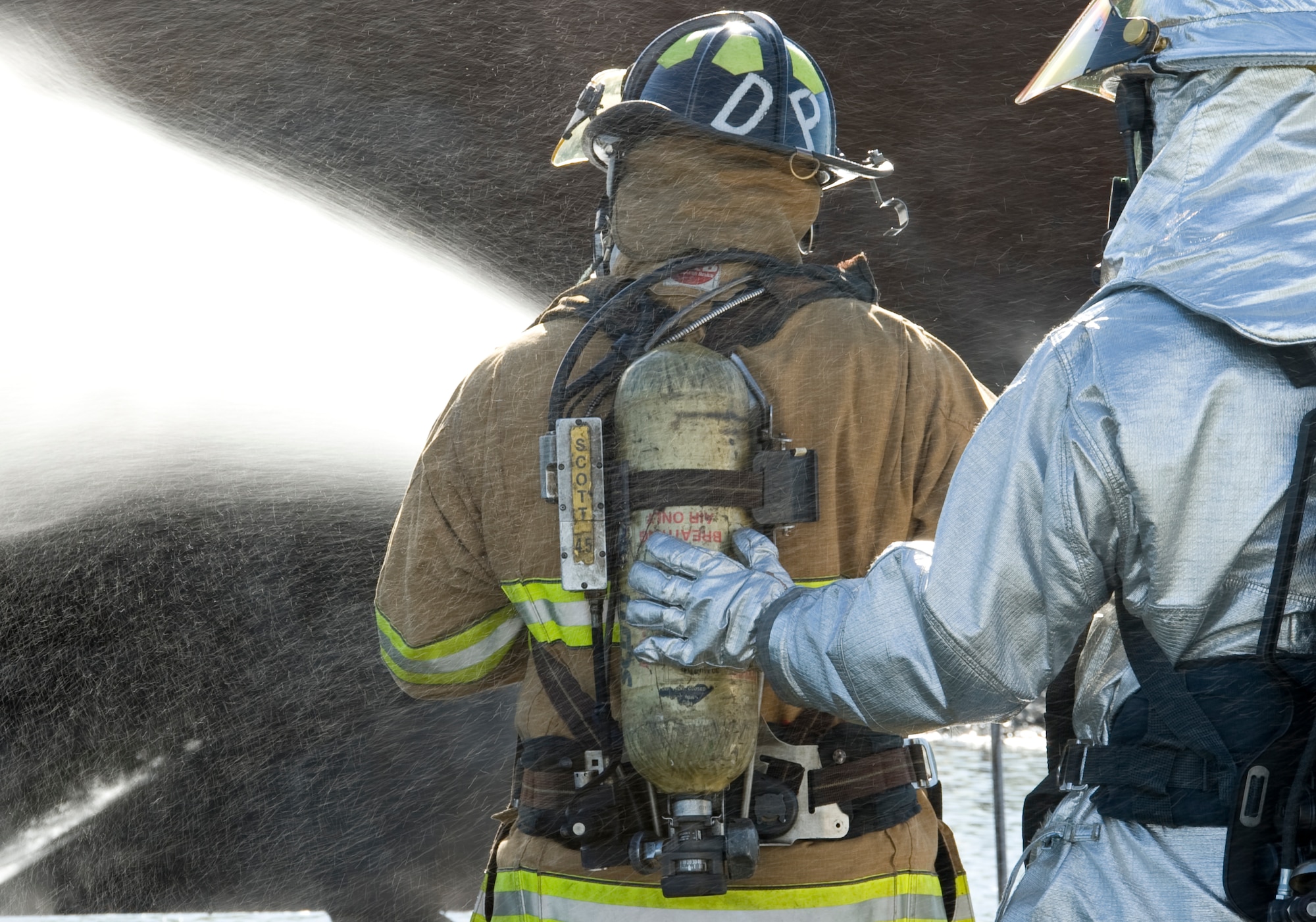 A firefighter from the 2nd Civil Engineer Squadron assists a firefighter from the Shreveport Fire Department on Barksdale Air Force Base, La., March 22. The pressure inside the hose can reach up to 150 psi and can be difficult for one person to keep under control.  (U.S. Air Force photo/Airman 1st Class Benjamin Gonsier)(RELEASED)
