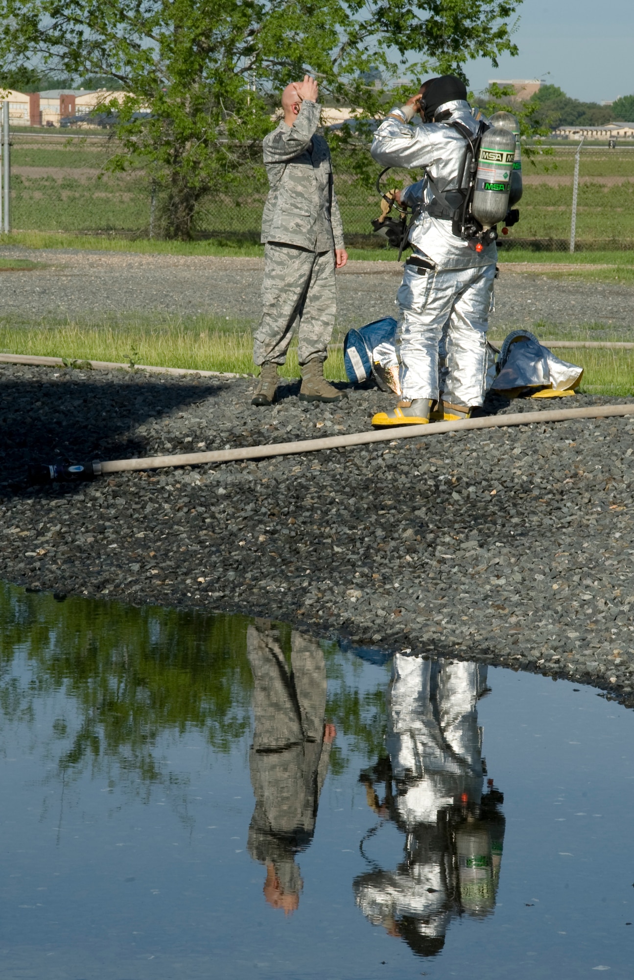 Firefighters from the 2nd Civil Engineer Squadron discuss safety precautions during an exercise on Barksdale Air Force Base, La., March 22. Firefighters that deal with aircraft fires wear fire proximity suits to protect themselves from temperatures that can reach up to 2,000 degrees Fahrenheit. (U.S. Air Force photo/Airman 1st Class Benjamin Gonsier)(RELEASED)