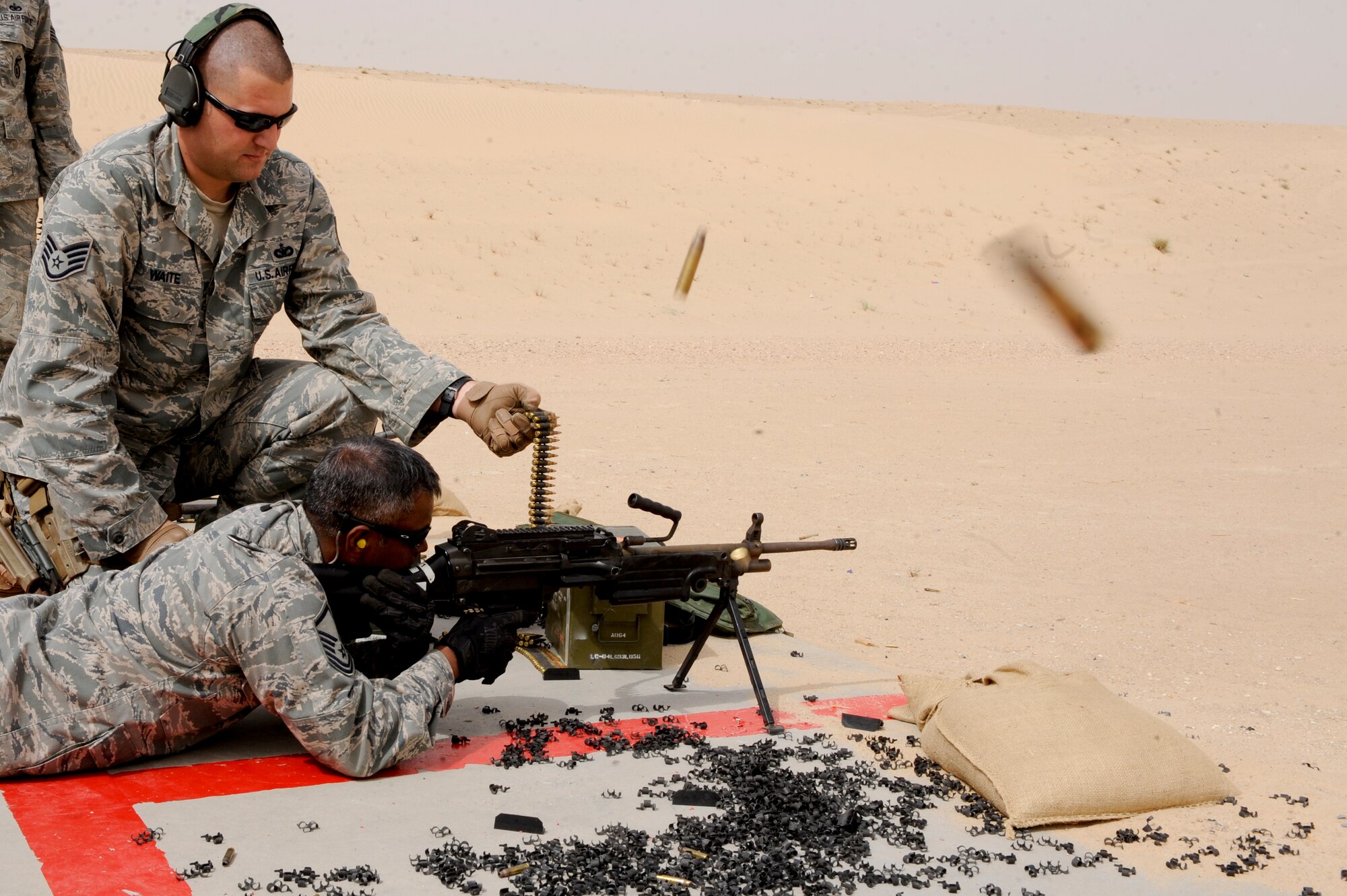 SOUTHWEST ASIA -- Staff Sgt. Todd Waite, 332nd Expeditionary Security Forces Squadron combat arms instructor, watches as Master Sgt. Jesse Divelbess, 332nd Air Expeditionary Wing chaplain assistant, fires an M249 machine gun at an undisclosed location in Southwest Asia, March 23, 2012. Waite is deployed from Holloman Air Force Base, and is a native of Jackson, Mich. Divelbess is deployed from the Iowa Air National Guard, and is a native of Omaha, Neb. (U.S. Air Force photo by Staff Sgt. Joshua J. Garcia)