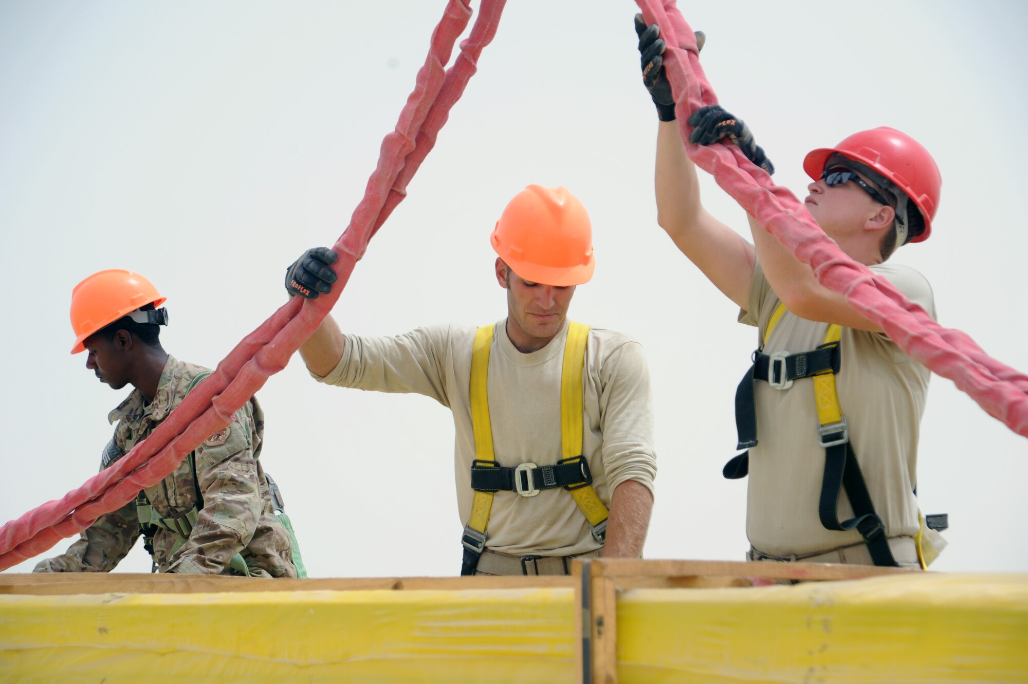 SOUTHWEST ASIA  - (From left to right) Senior Airman James Morris, Staff Sgt. Luke Oaks and Staff Sgt. Kerstin Pieren guide insulated roof panels onto a construction site March 22, 2012. Roughly 30 members of the 557th Expeditionary RED HORSE Squadron, or Rapid Engineer Deployable Heavy Operations Repair Squadron Engineers, are deployed to assist the 380th Air Expeditionary Wing by constructing three, 20,000 square-foot warehouses to store items sensitive to the harsh weather conditions in the area. (U.S. Air Force photo/1st Lt. Victoria Porto)